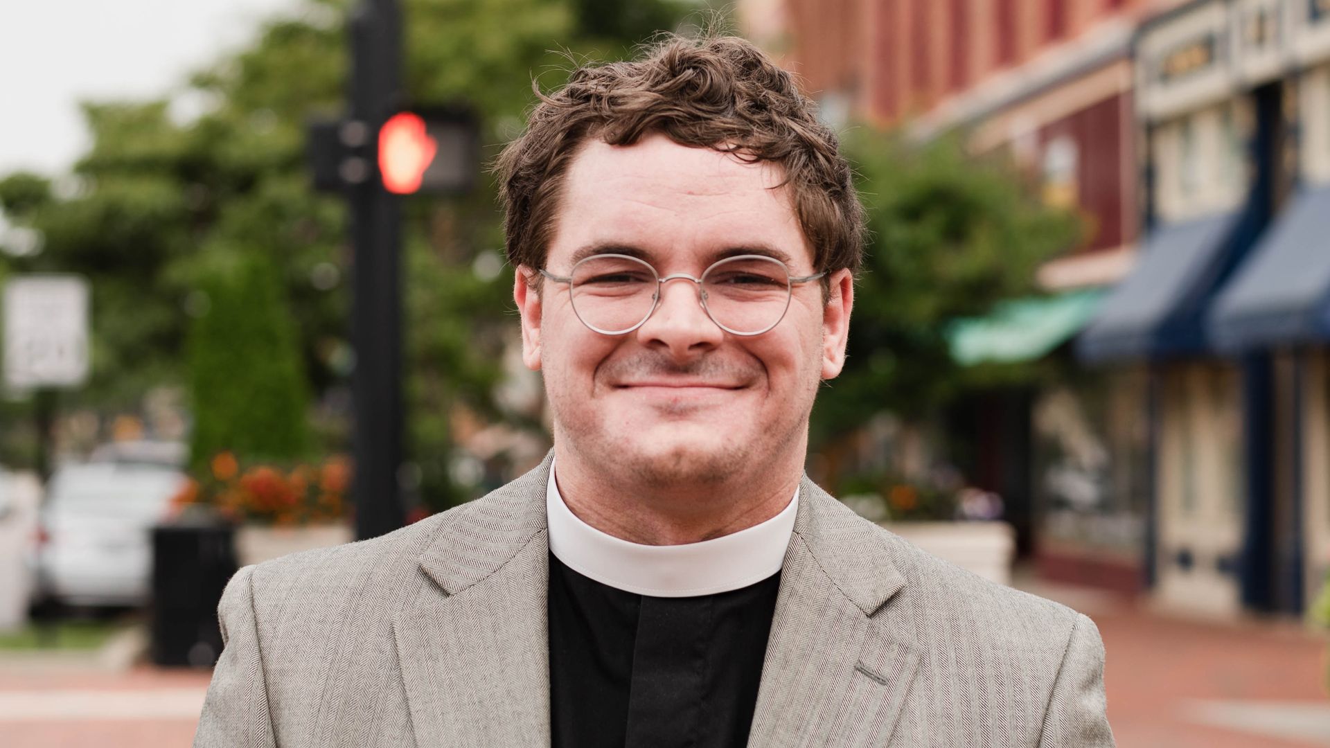 Rev. Rob E. Lee stands in a downtown with his clergy clothes on.