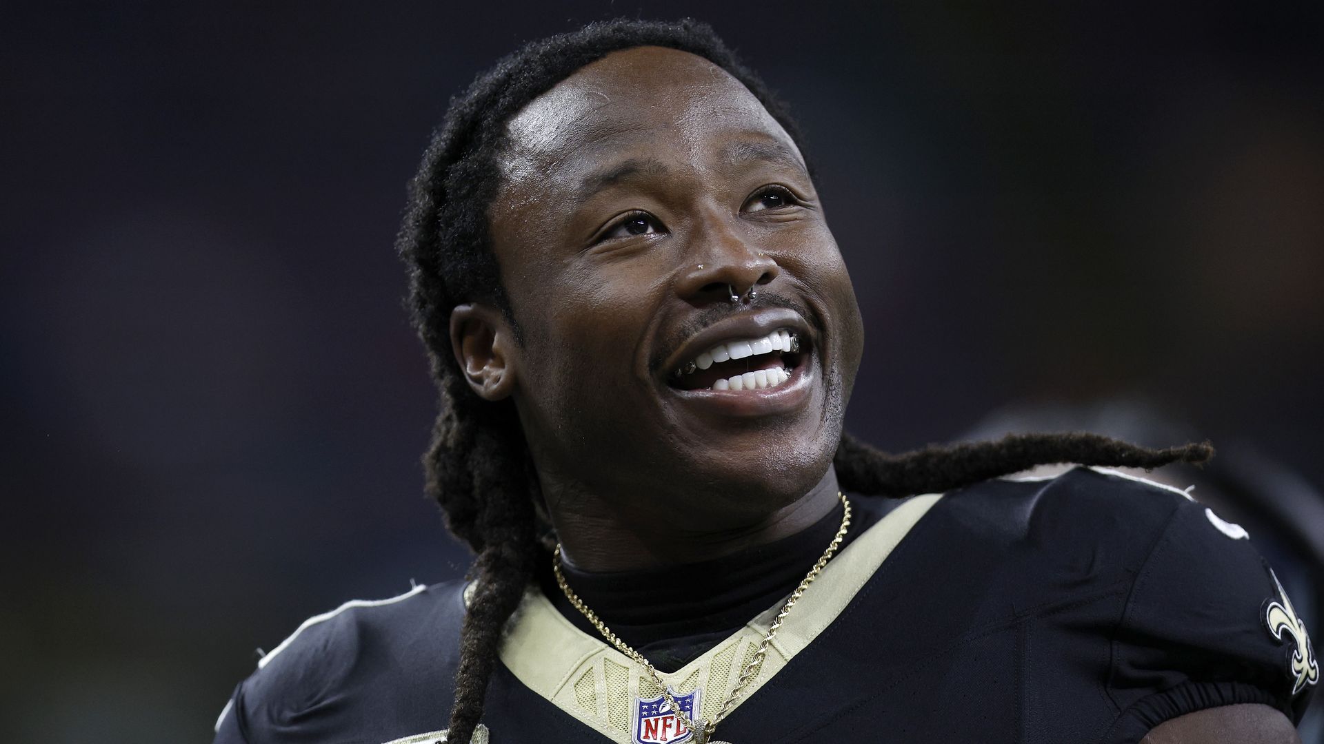 A close-up photo of Alvin Kamara smiling with his helmet off during a game.