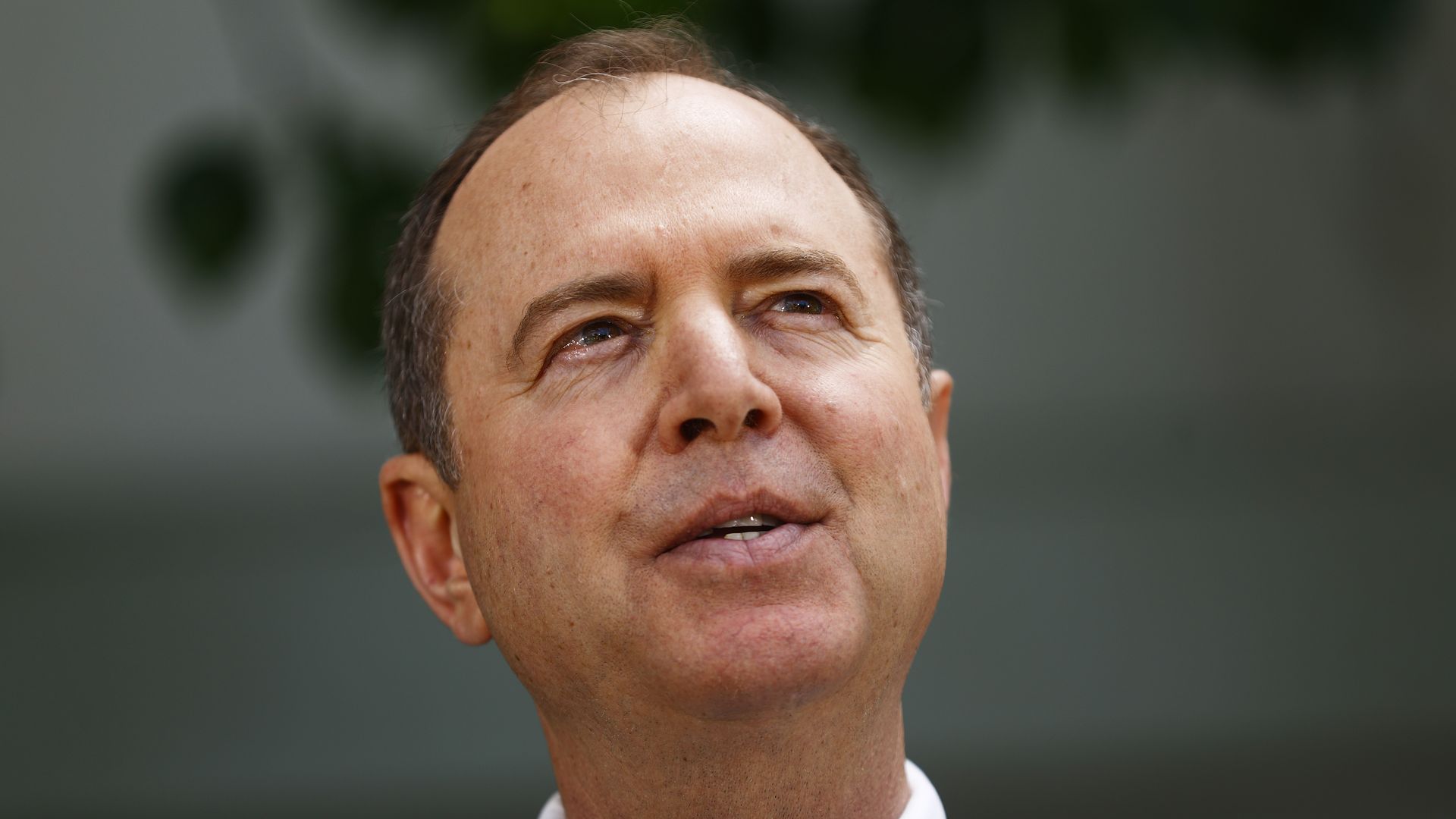 In this image, Adam Schiff stands and speaks while looking to the right.