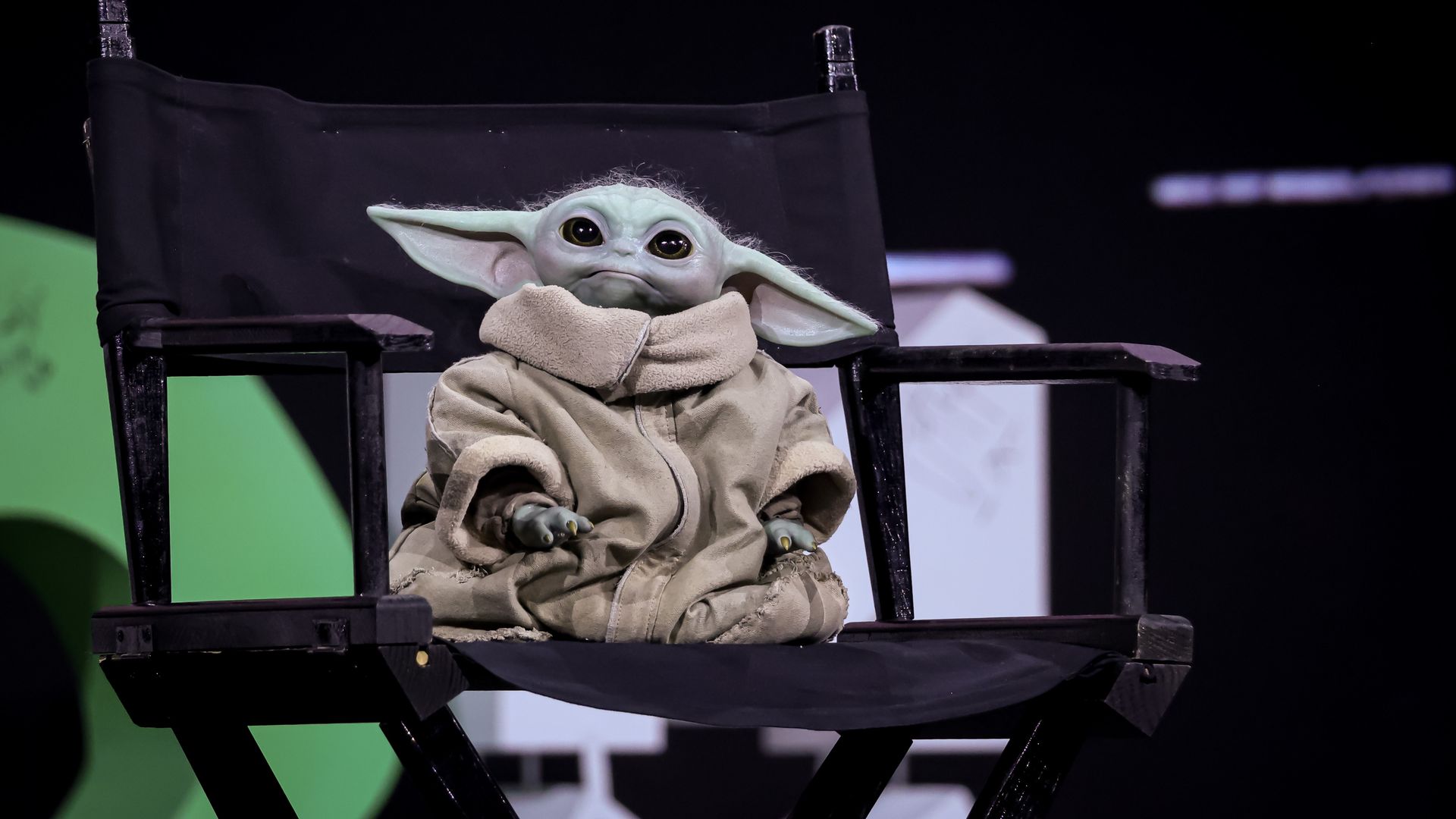 Star Wars character Grogu sits in a black director's chair.