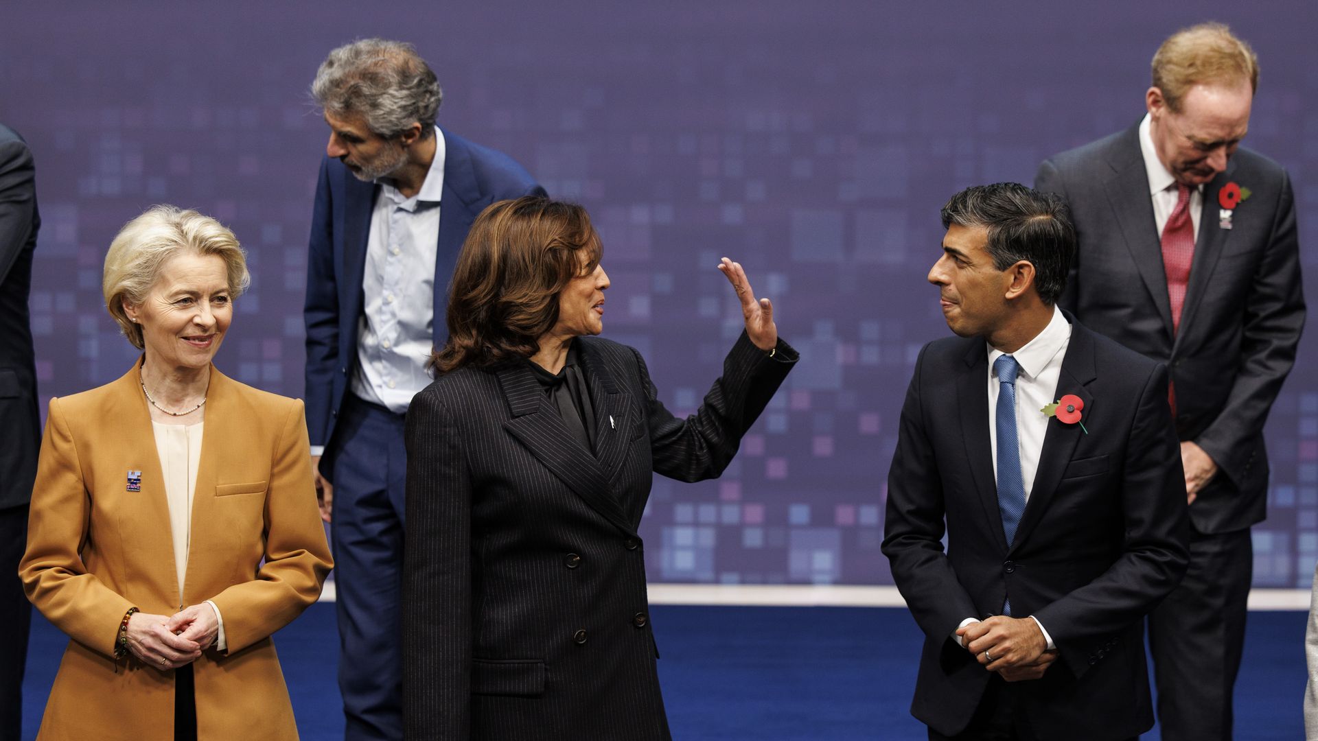 Five people on a stage, one with a hand up