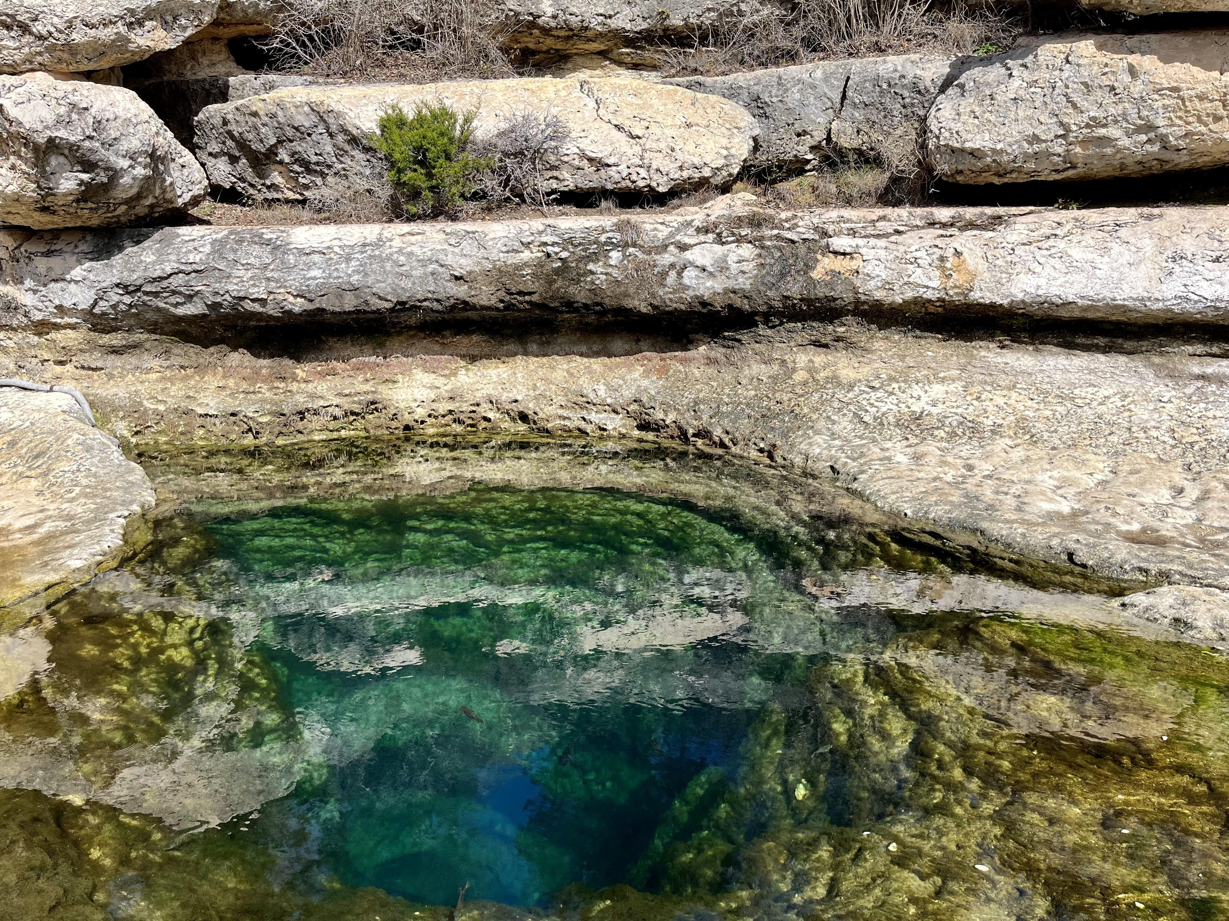 Jacob's Well is seen surrounded by tall rocks.