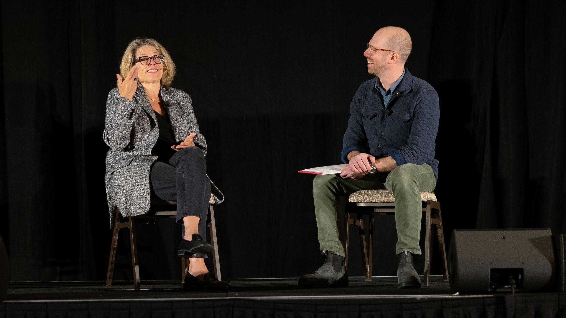 A photograph of Katie Rae of Engine Ventures and Alan Neuhauser of Axios, sitting in chair on stage at an event in Boston.