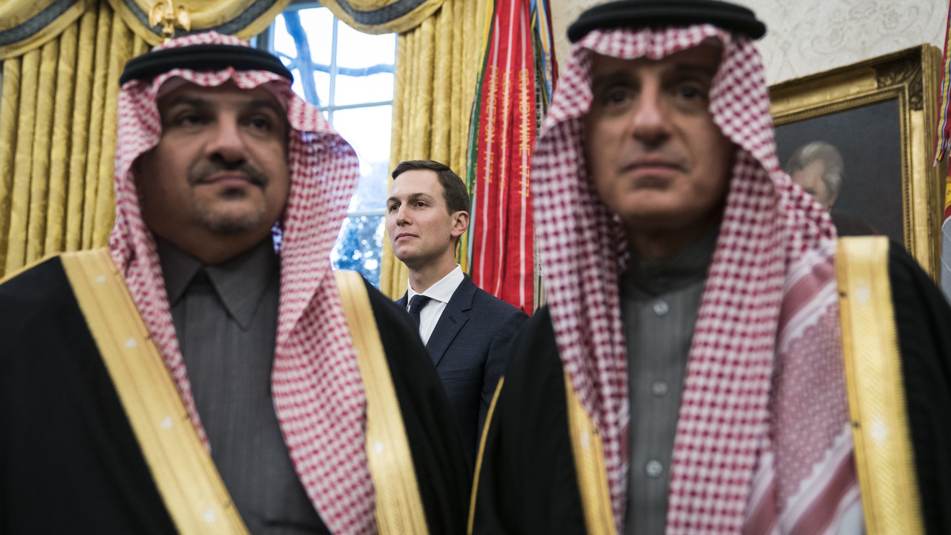 Jared Kushner stands behind two Saudi men.