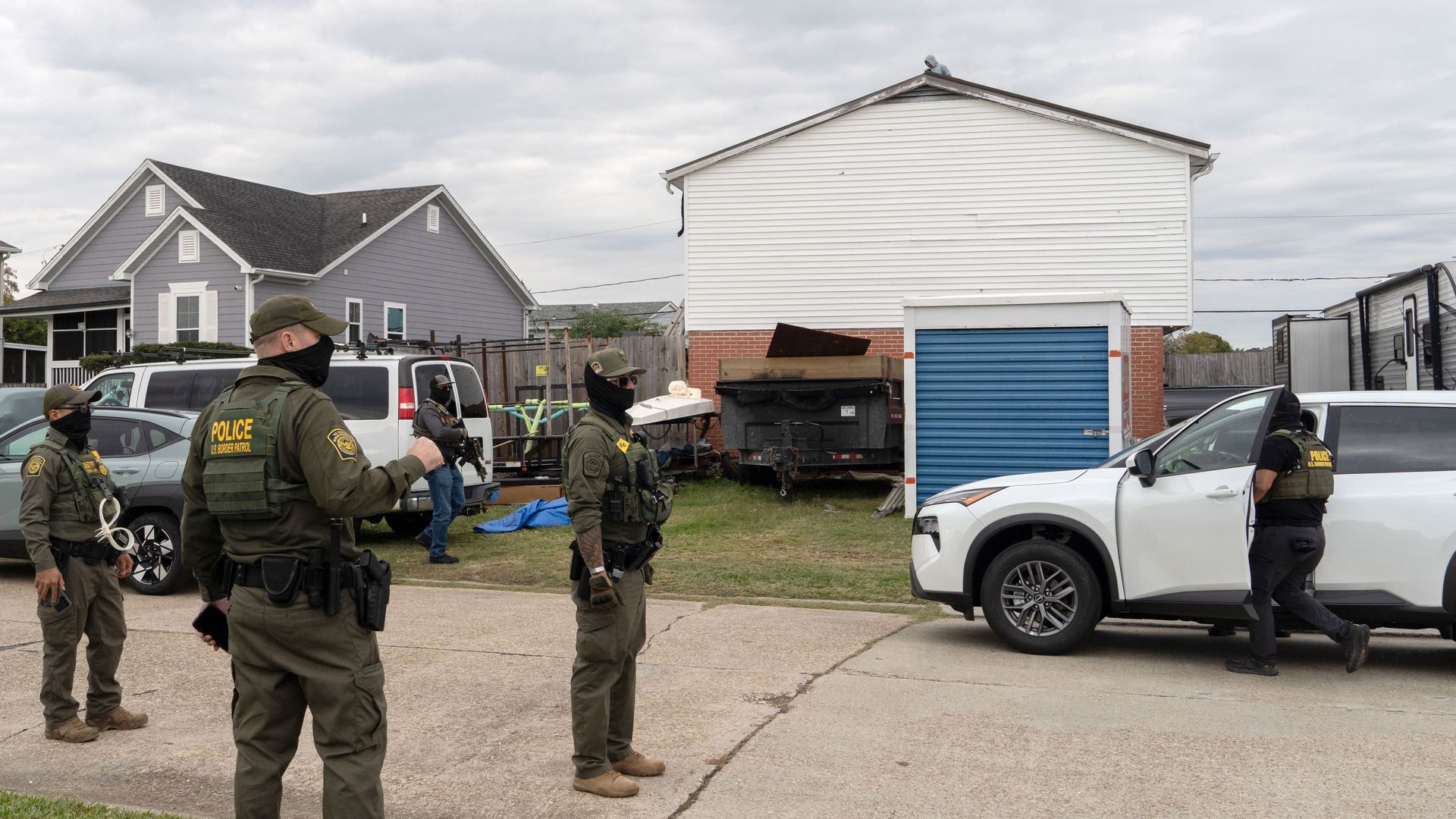 Federal agents stand in a roadway in a residential neighborhood.