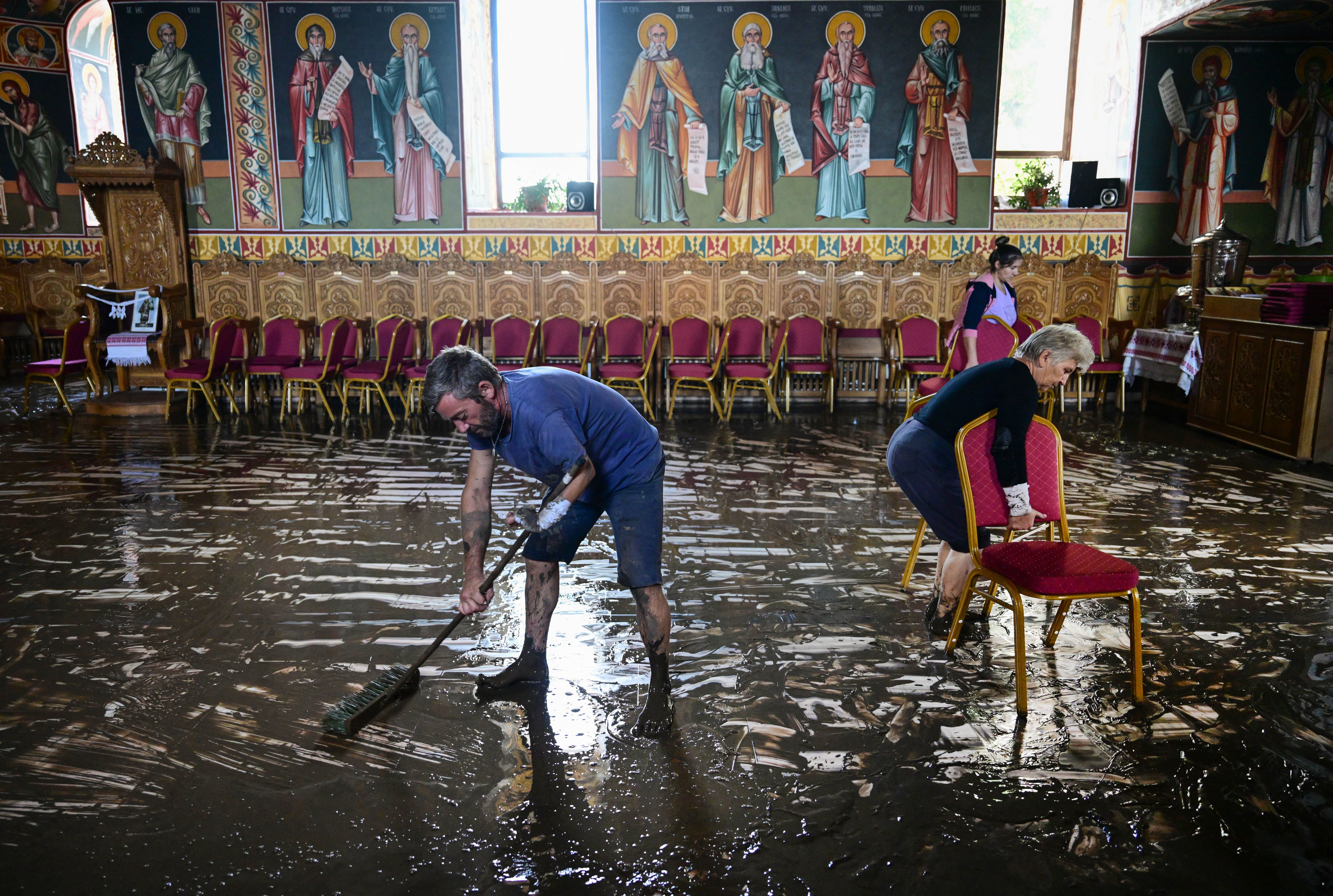 People clean the floor of a church after the flood water withdrew from the village of Pechea, Romania, on September 15