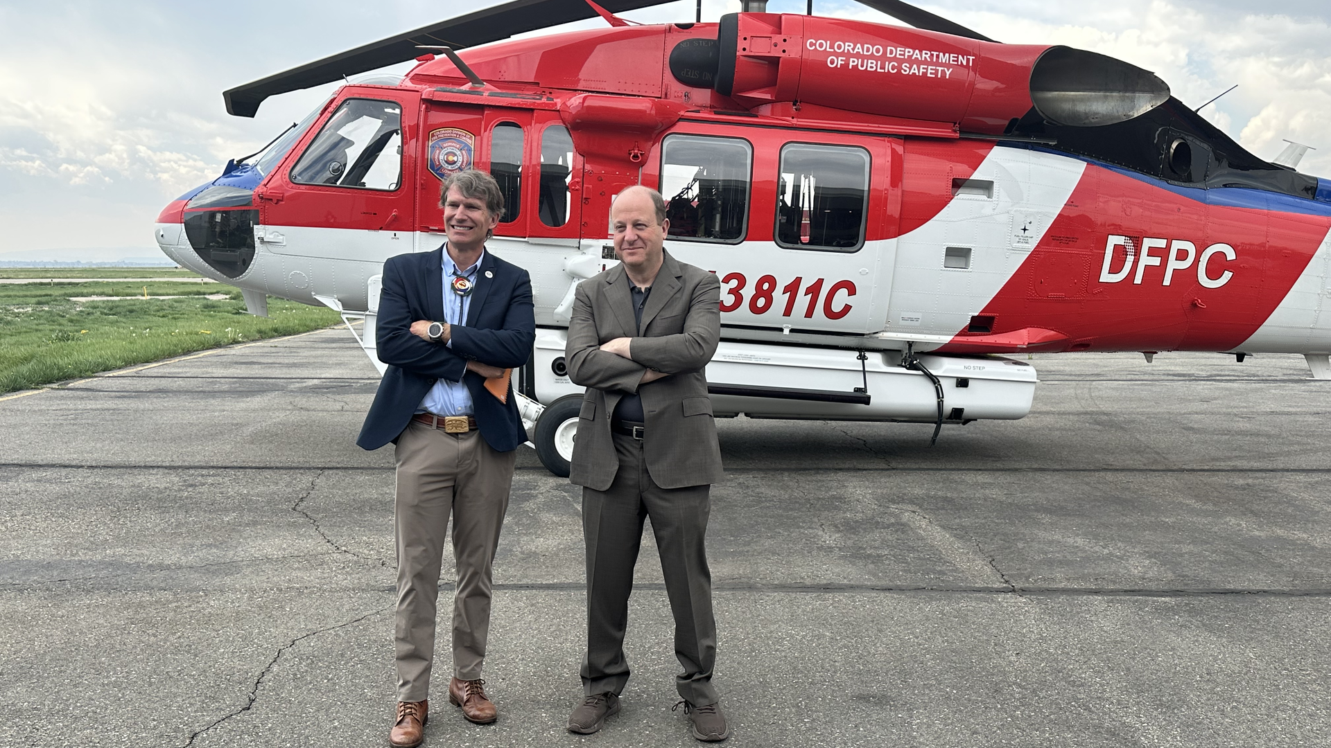 Gov. Polis stands in front of a firehawk helicopter