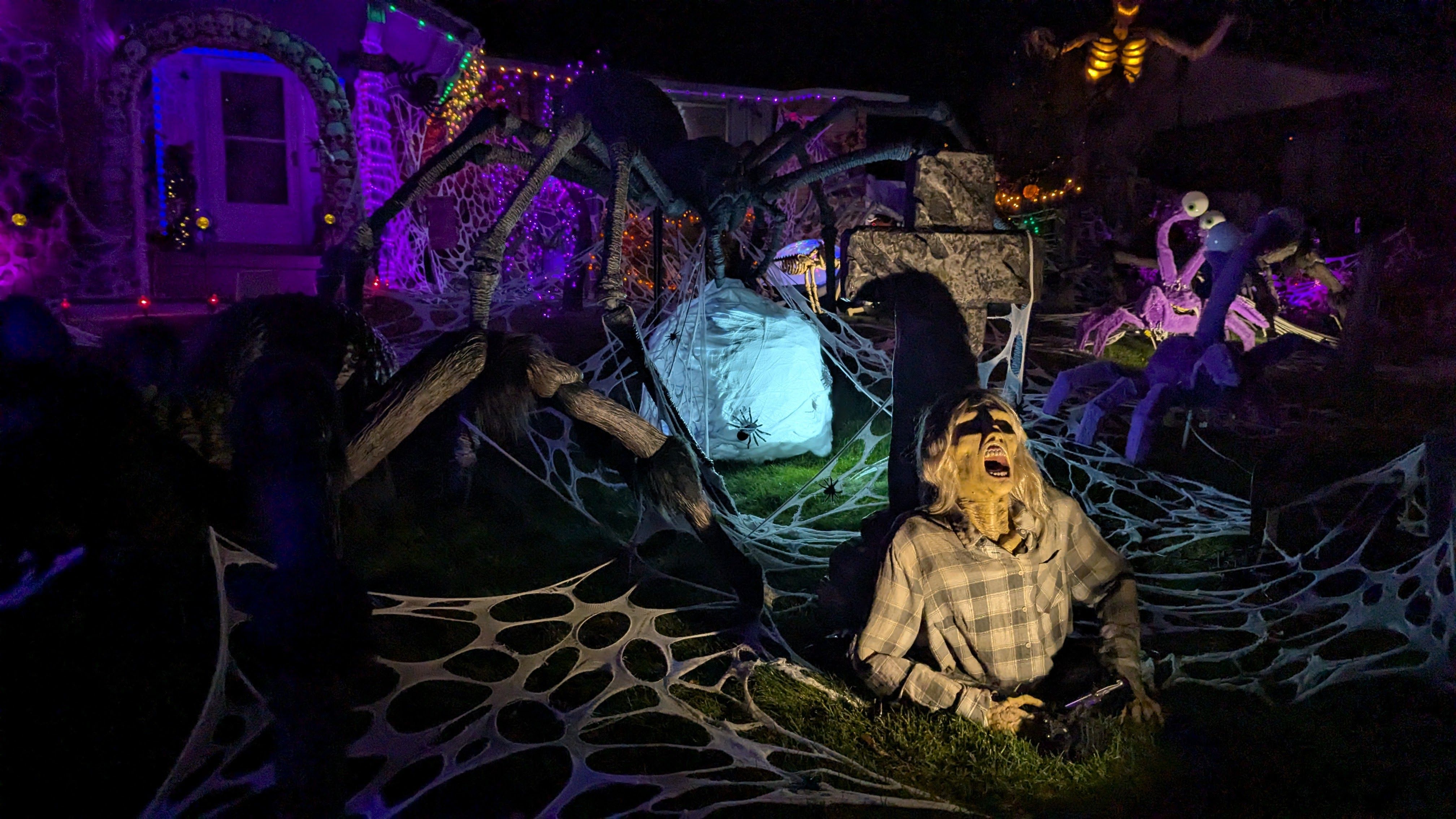 A zombie bursts out of a grave at a house decorated for Halloween.