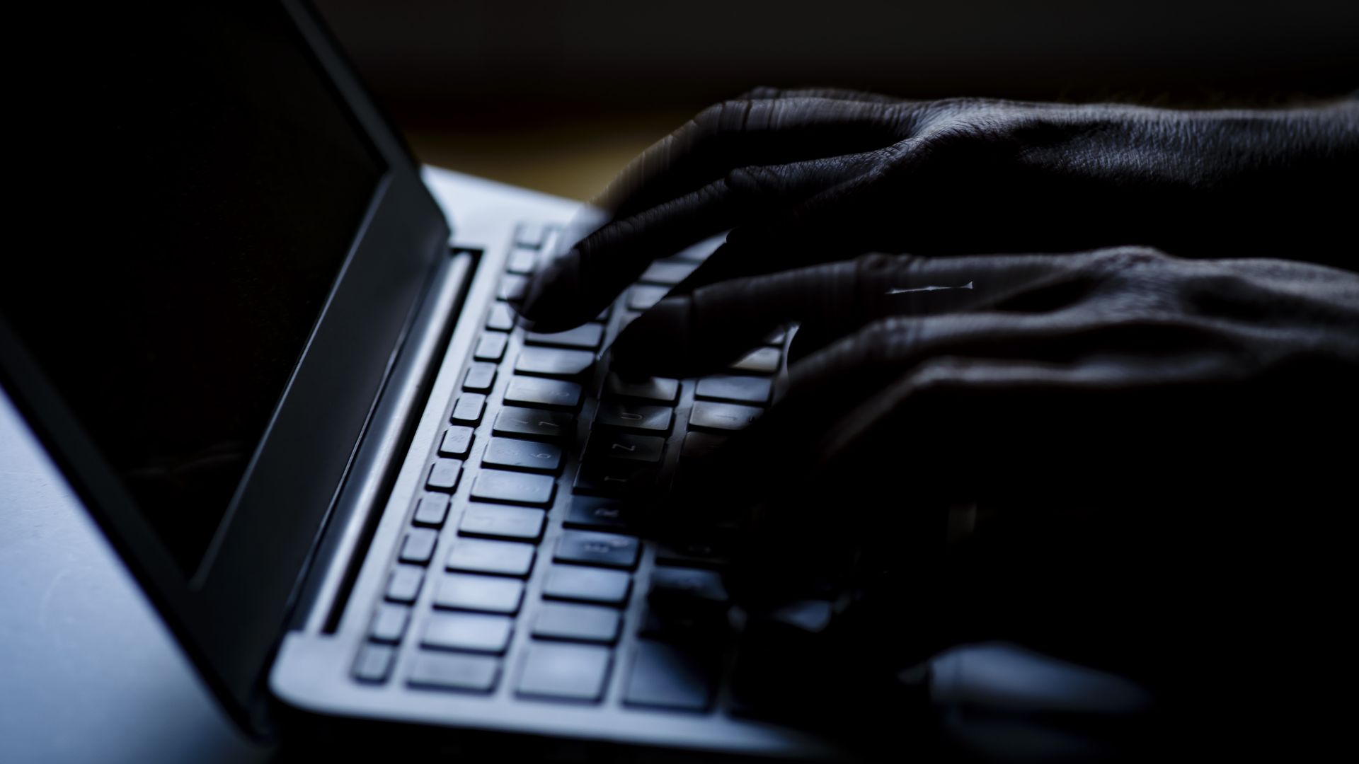 Fingers typing on a keyboard in the dark