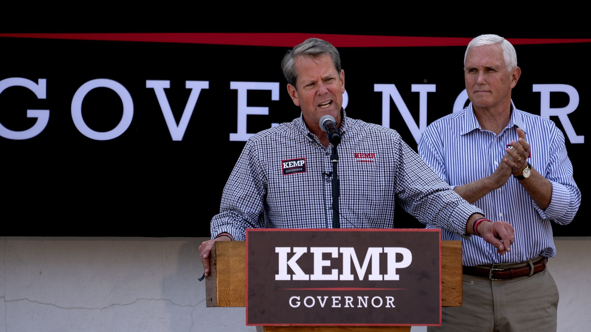 Mike Pence stands behind Brian Kemp and they are both behind a podium that says KEMP Governor.
