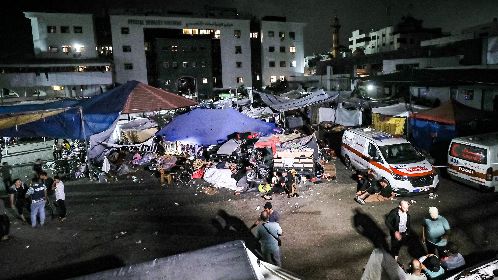 People wait in tent shelters in the darkness as fuel for electricity generation runs out, outside Al-Shifa hopsital in Gaza City early on November 3, 2023,