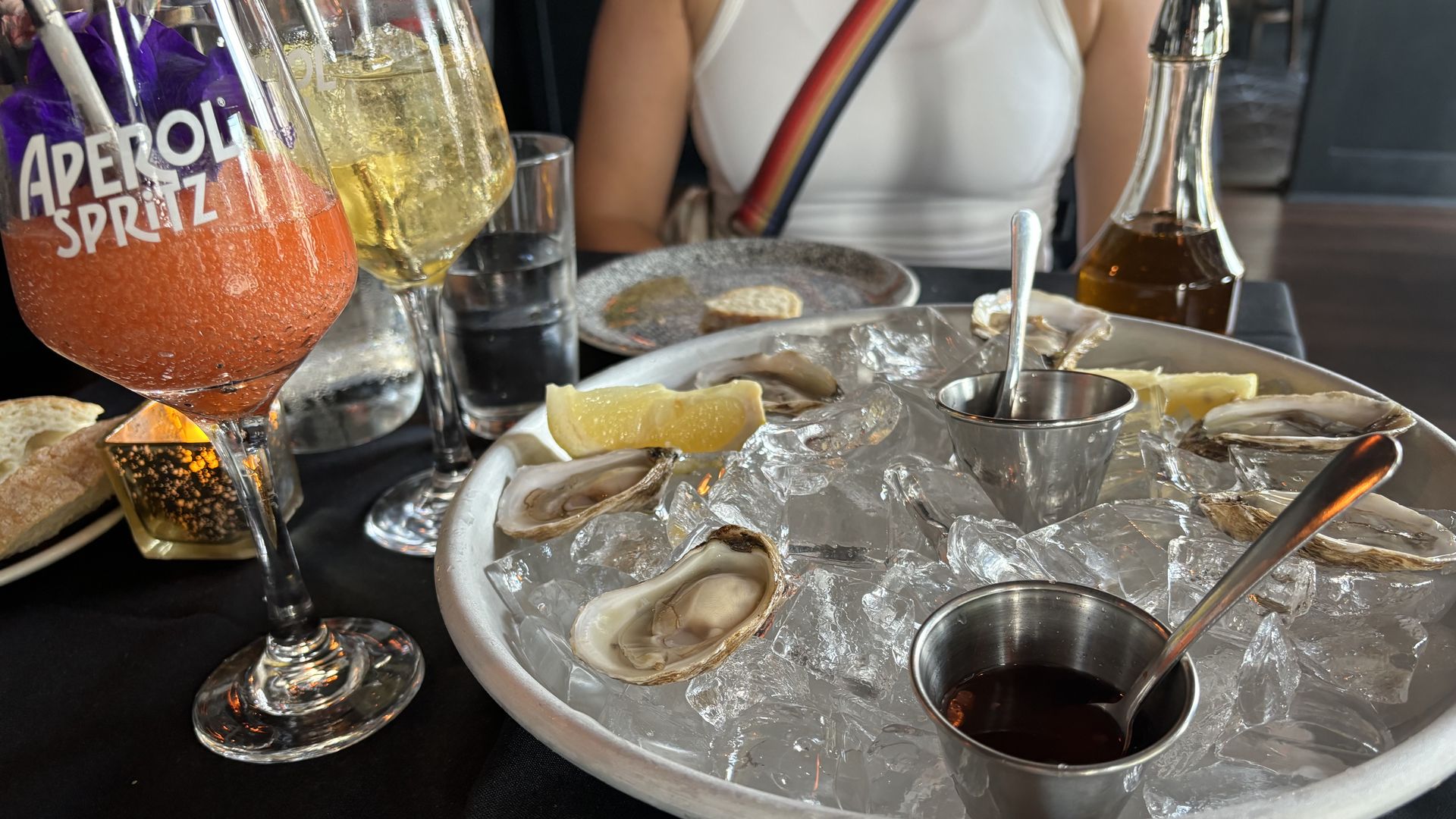 Two drinks and a plate of oysters on ice. 