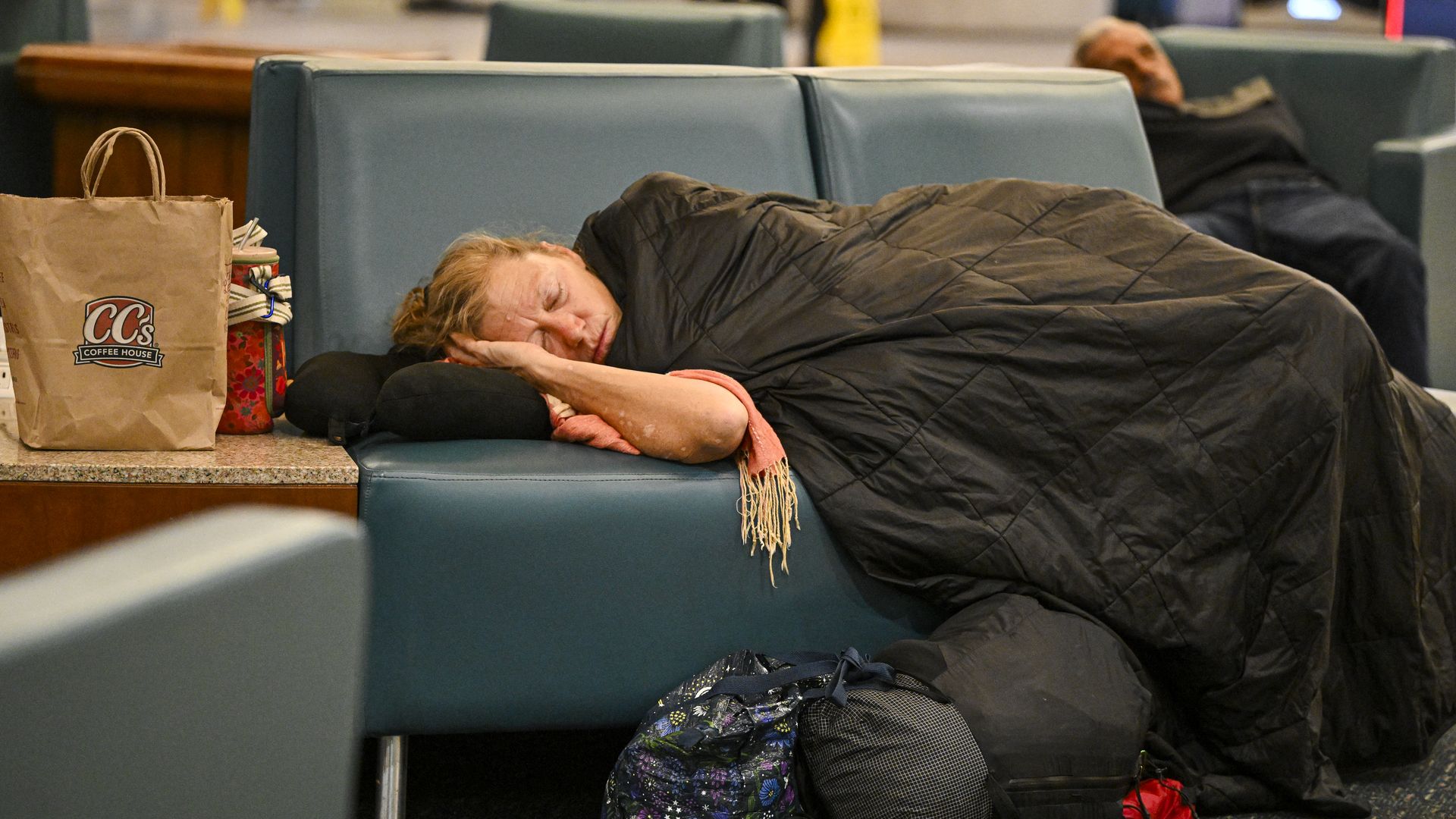 People sleep on chairs in an airport terminal as flights are delayed at Orlando International Airport during the U.S. government shutdown.