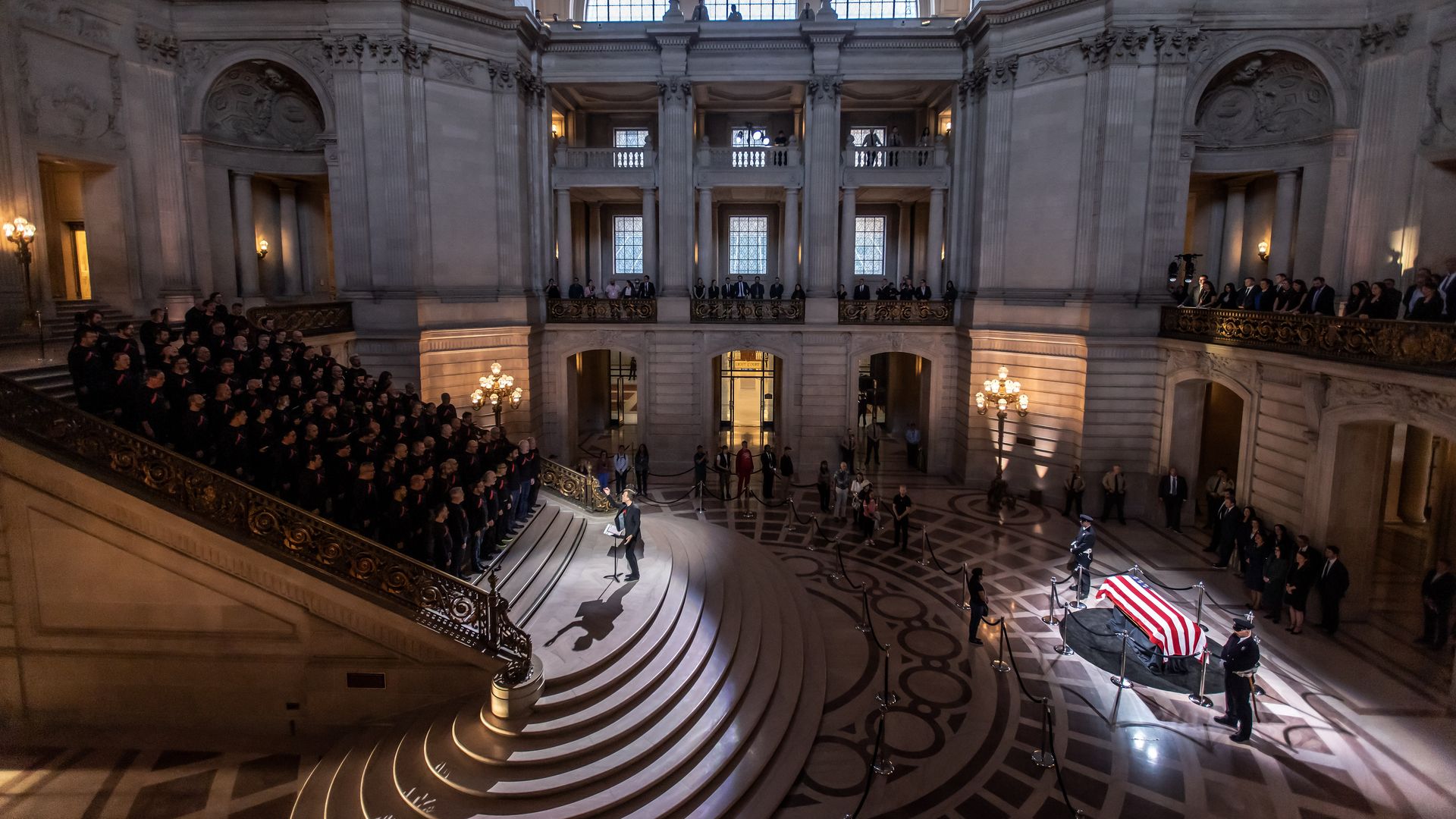 Choir stands on left on stairs with Pelosi's casket on the right.