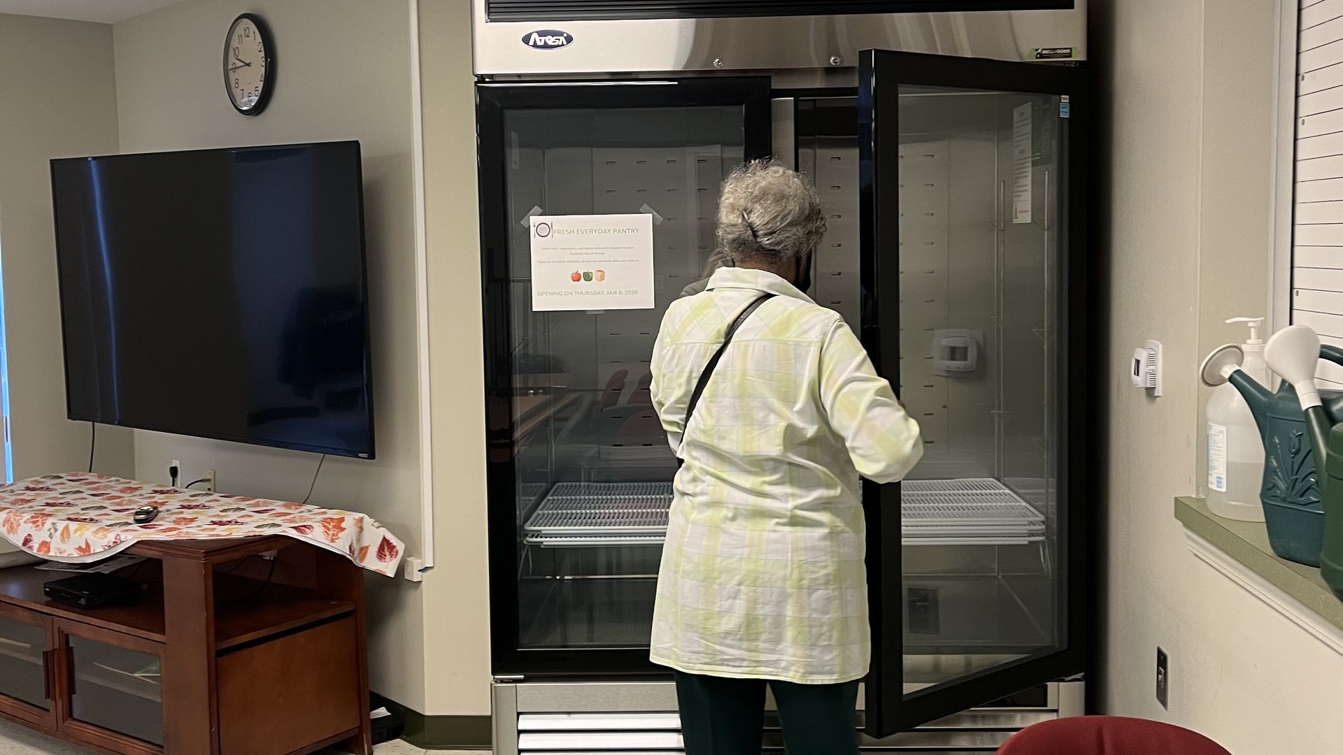 A person stands in front of a fridge with glass doors.