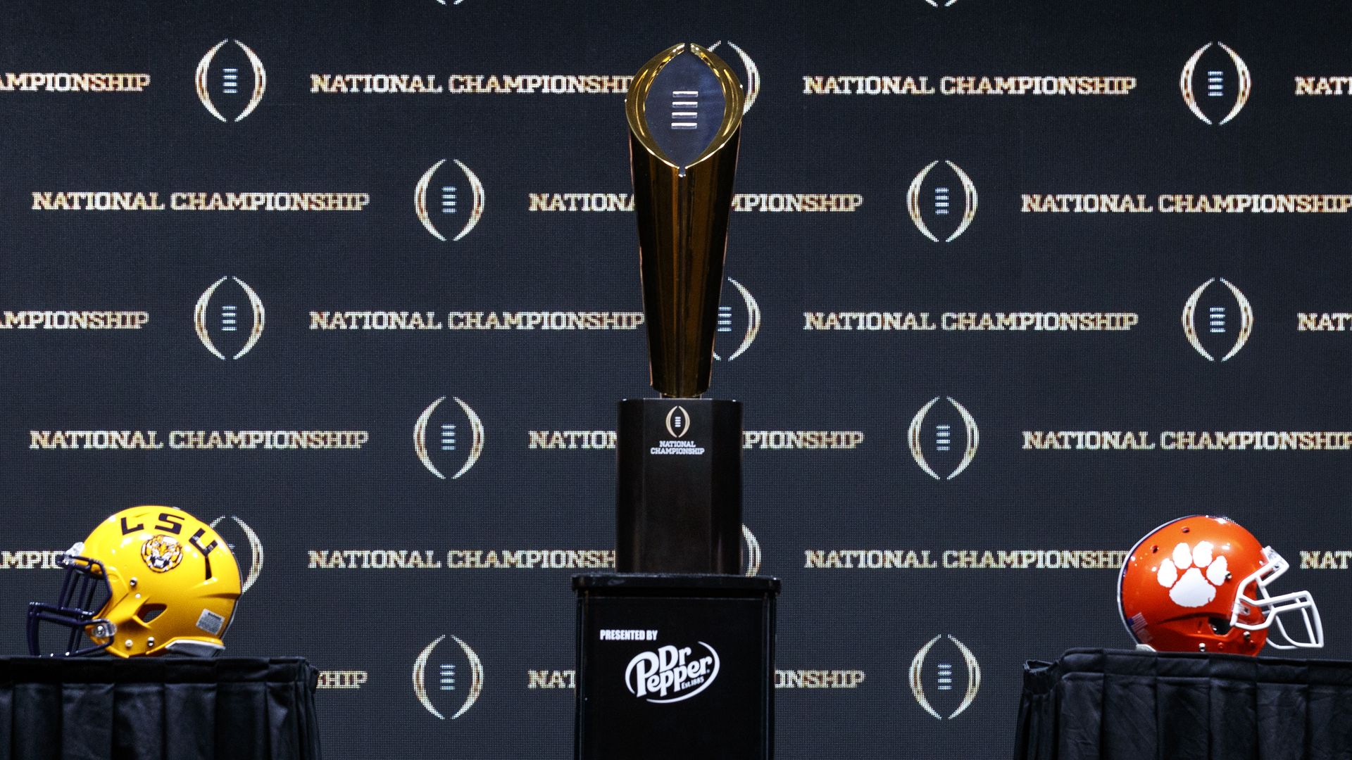 LSU and Clemson helmets on either side of the CFP trophy