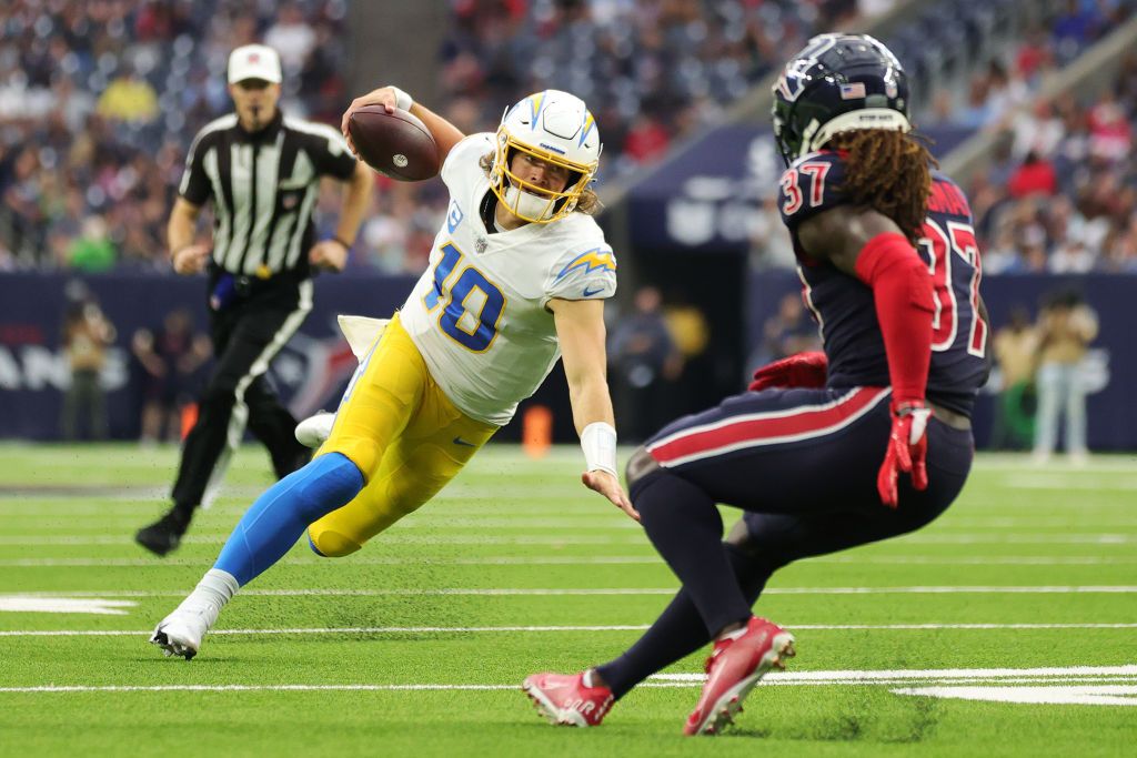 Justin Herbert #10 of the Los Angeles Chargers runs the ball ahead of Tavierre Thomas #37 of the Houston Texans during the fourth quarter at NRG Stadium on December 26, 2021 in Houston, Texas. 