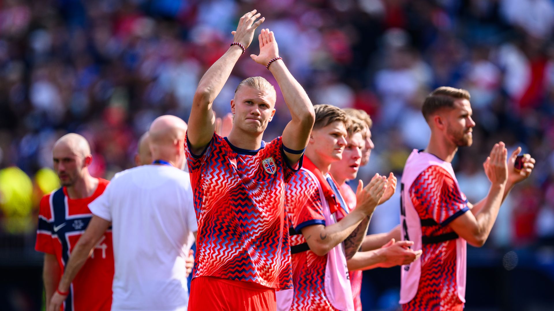 Erling Haaland looks up and claps while on a field