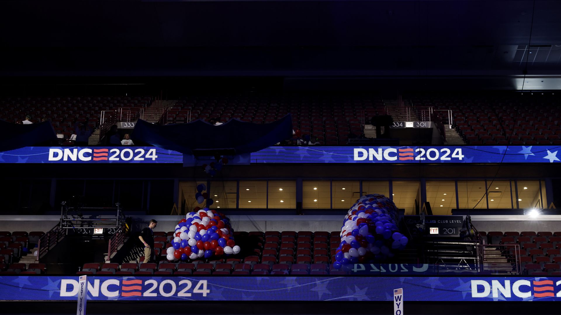 Balloons being set up in the stands of a darkened stadium with "DNC 2024" logos.