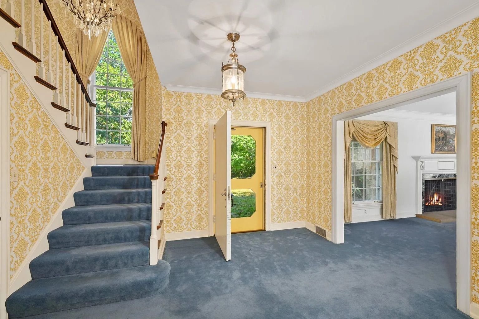 The foyer of a home with yellow wallpaper and gray carpet.