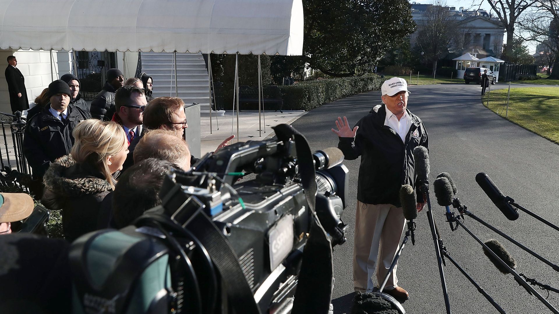 Trump waves hand in air before cameras and mics.