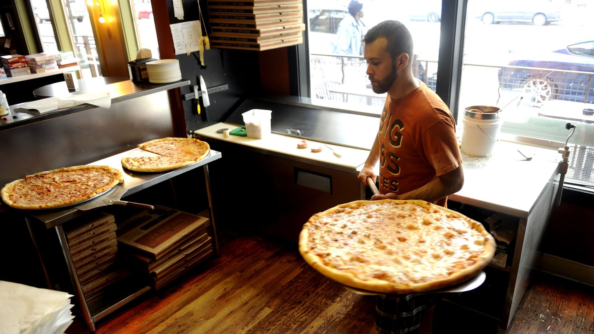 An employee carries a large pizza