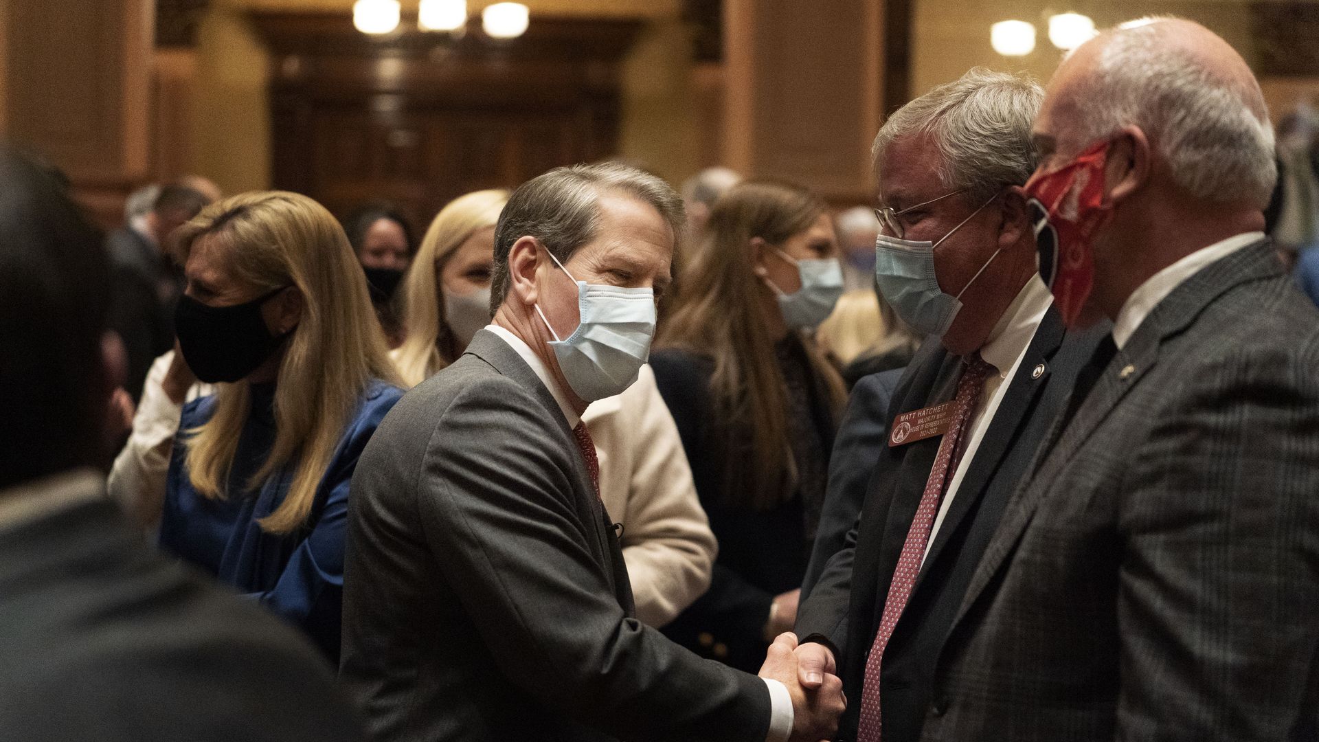 Brian kemp shakes hands with two men, all wearing masks