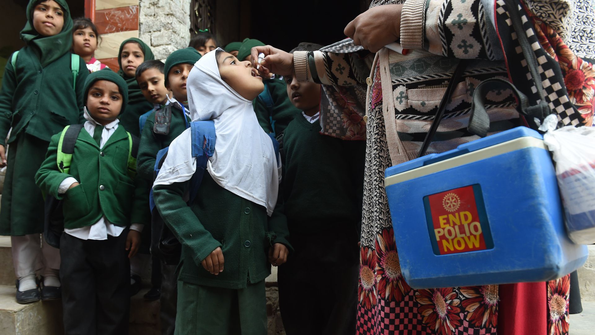 A Pakistani health worker administers polio vaccine drops to school children during a polio campaign.