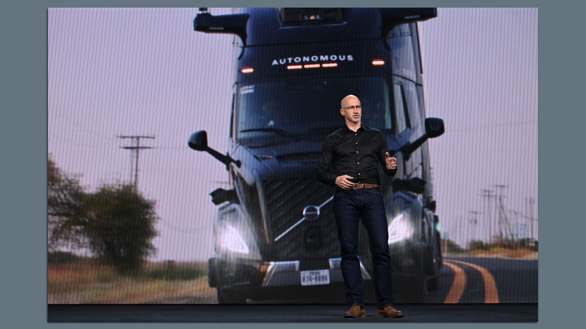 Image of Sterling Anderson, the co-founder of Aurora Innovation, talking in front of a giant screen showing a self-driving semi-truck. 