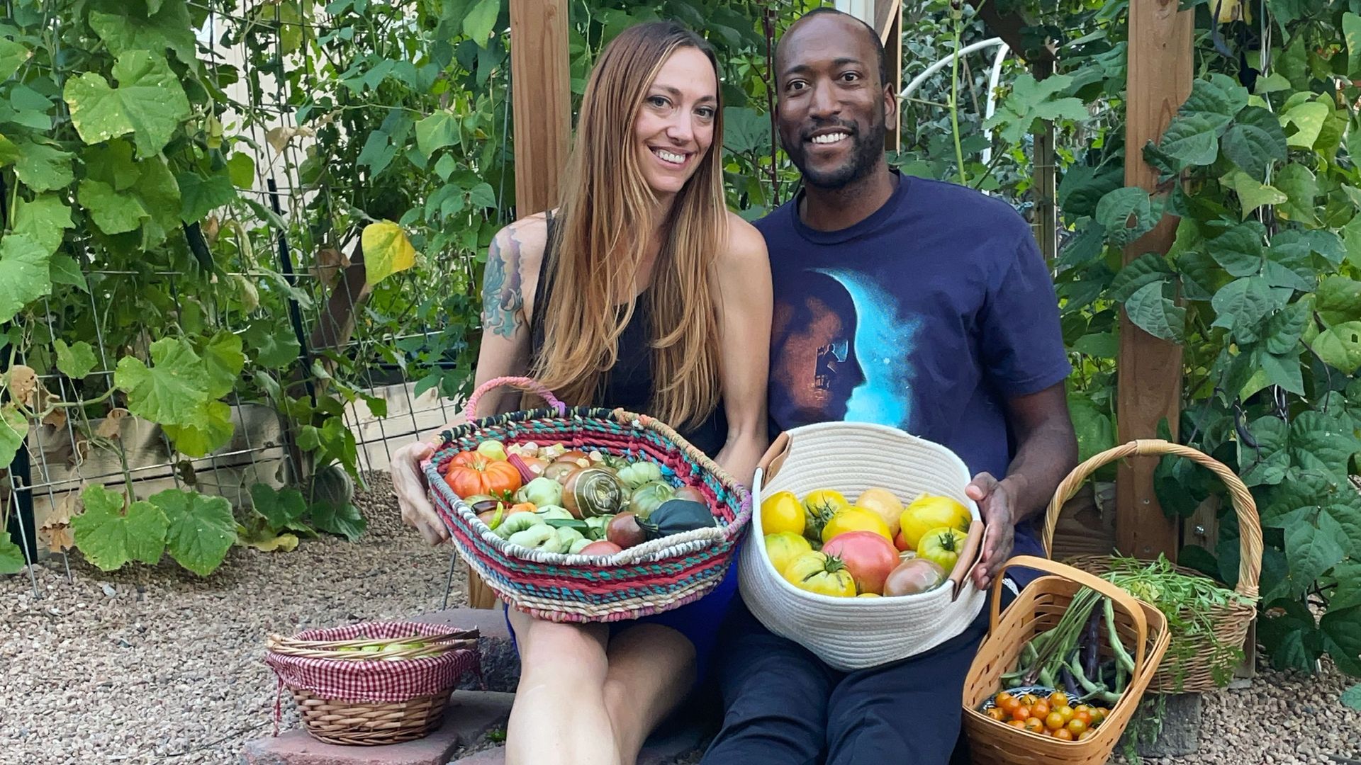 couple showing off their homesteading harvest sitting in a garden