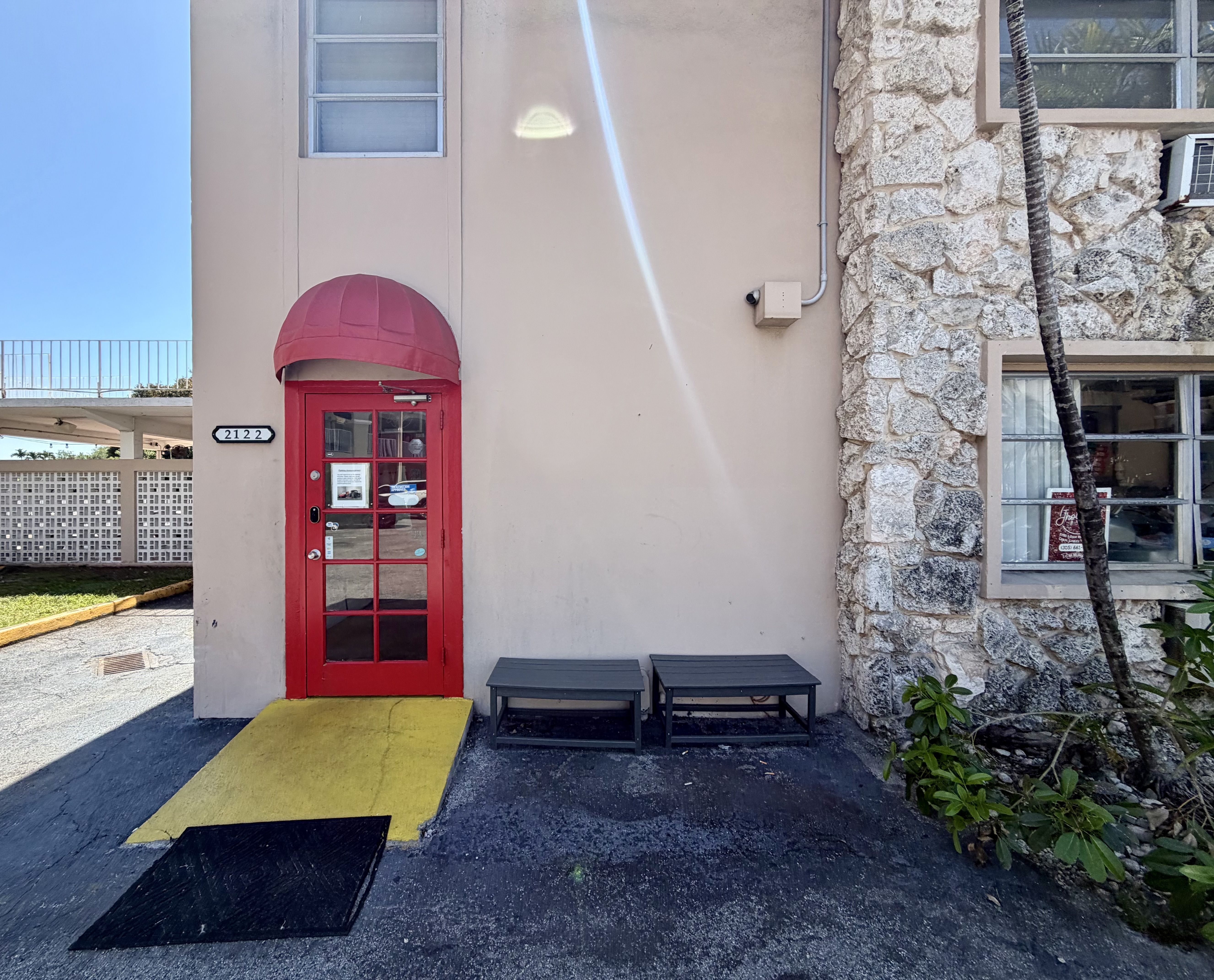 Beige building with a bright red door under a rounded red canopy.