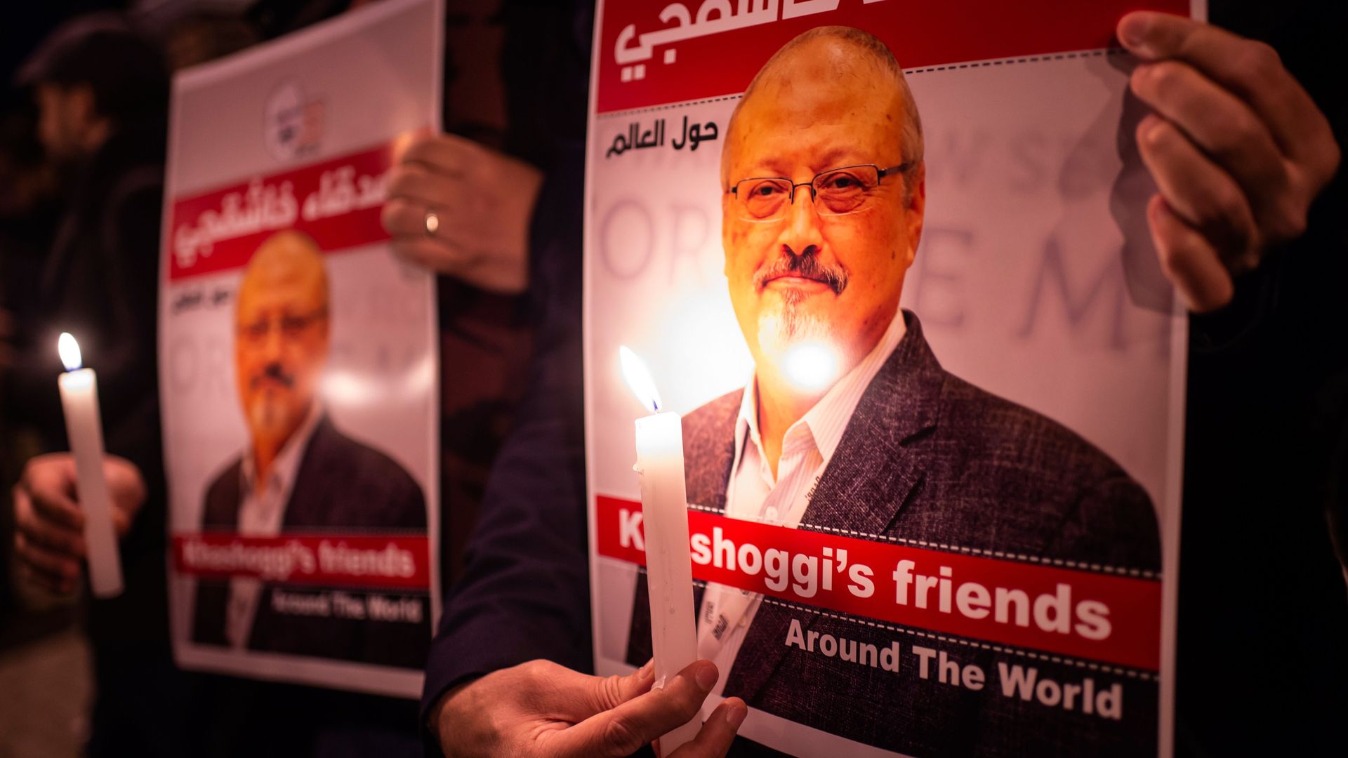 A person holds a candle in front of a poster of murdered journalist Jamal Khashoggi.