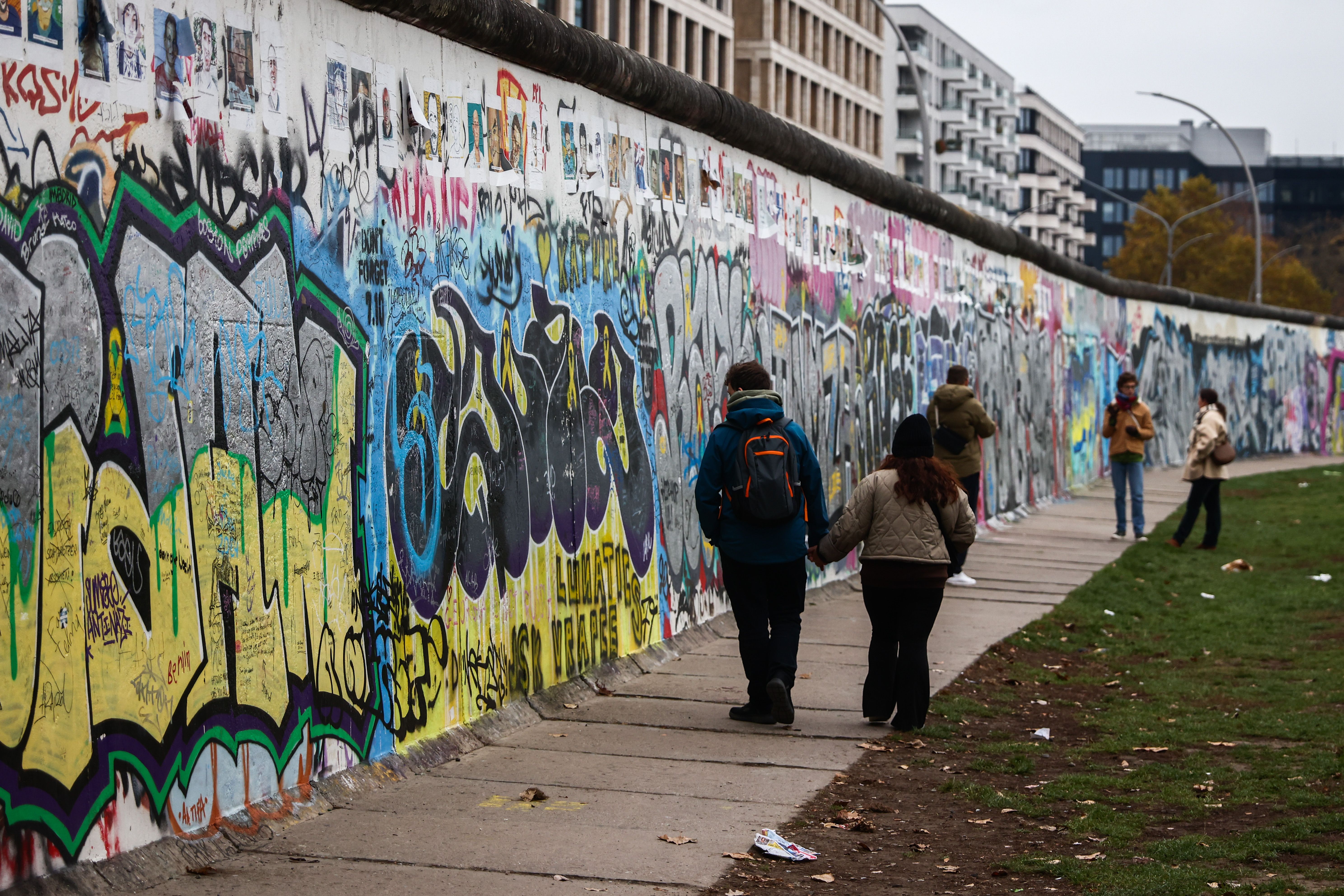 People walk by a yellow and blue mural