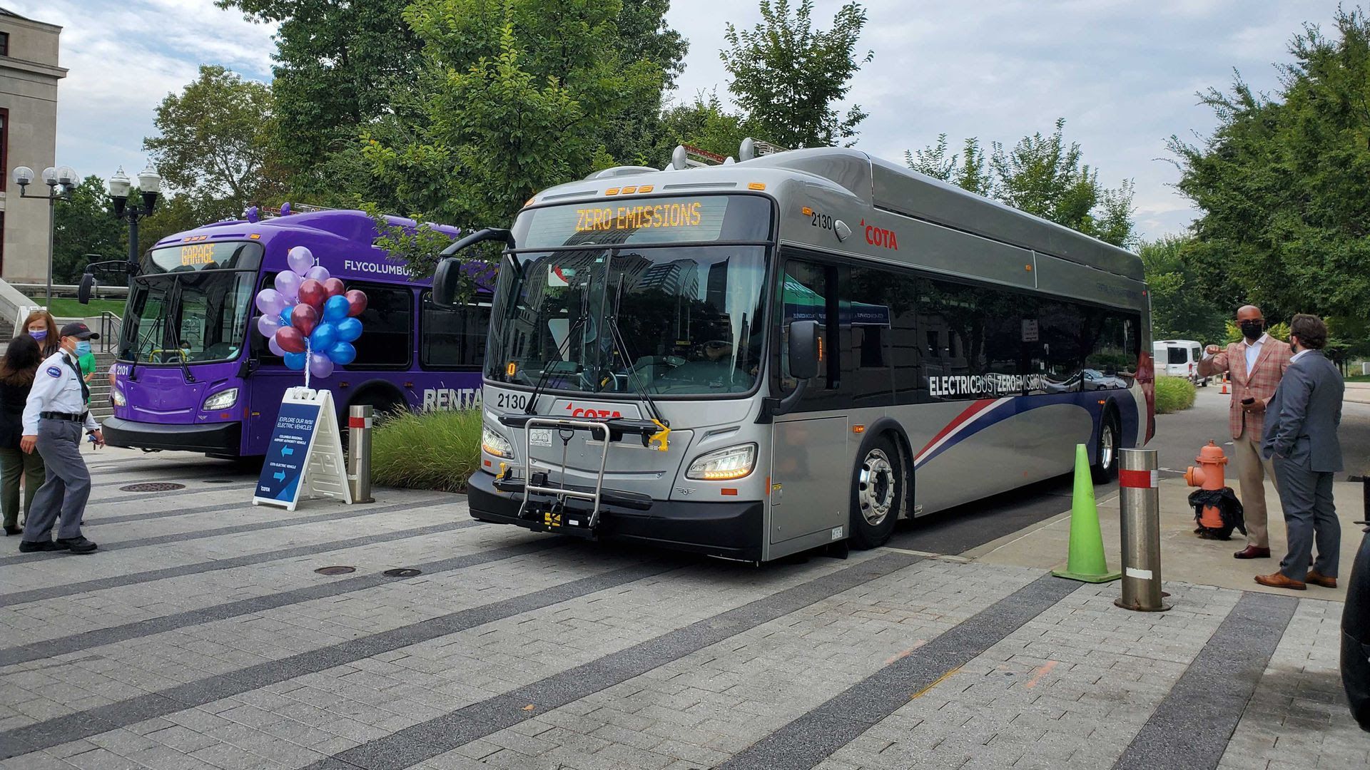 Two electric buses are seen Wednesday morning outside of Columbus City Hall. The COTA bus on the right will begin carrying passengers next week.
