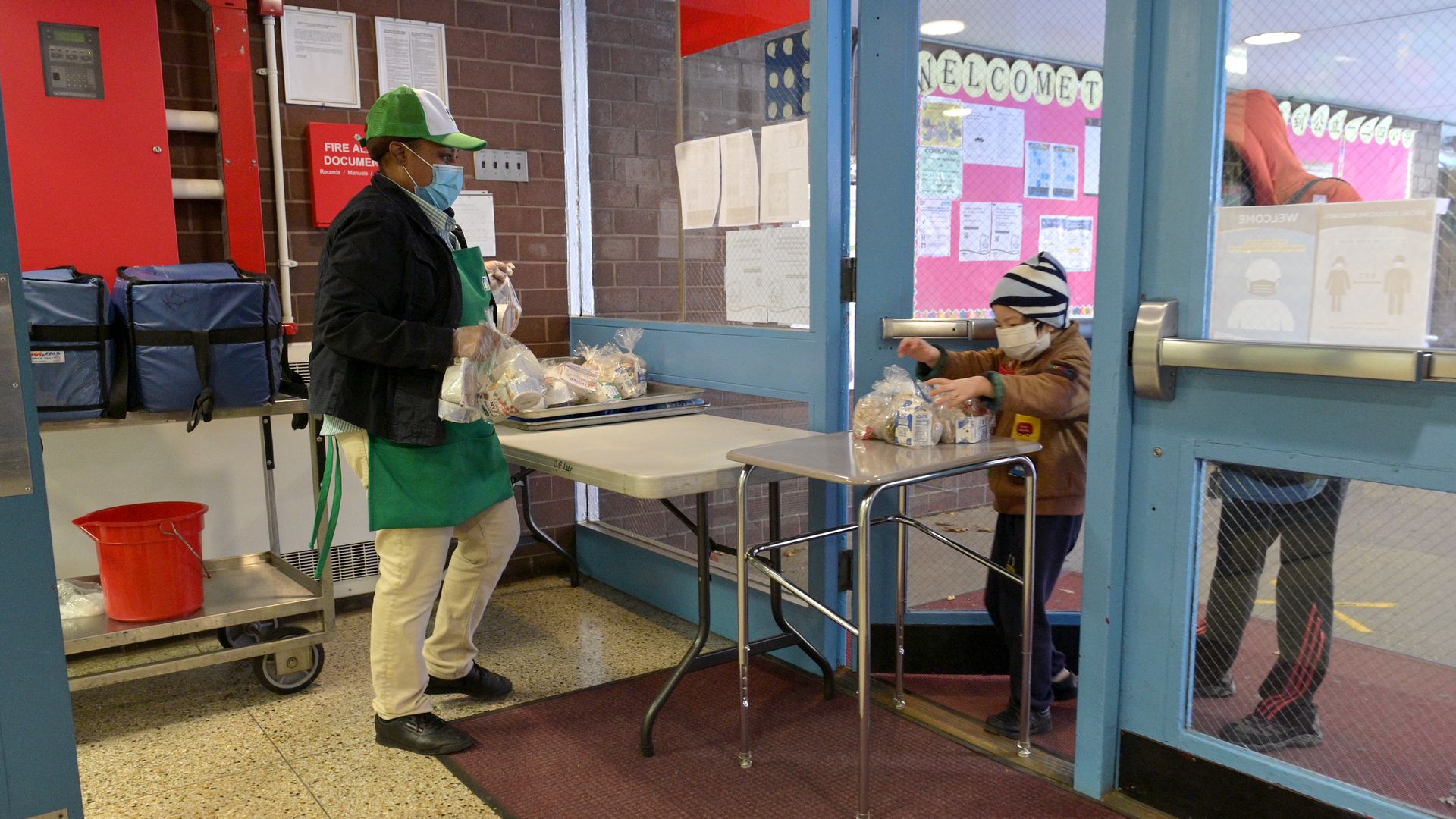 A student chaperoned by an adult picks up a meal to go at a school in New York City.