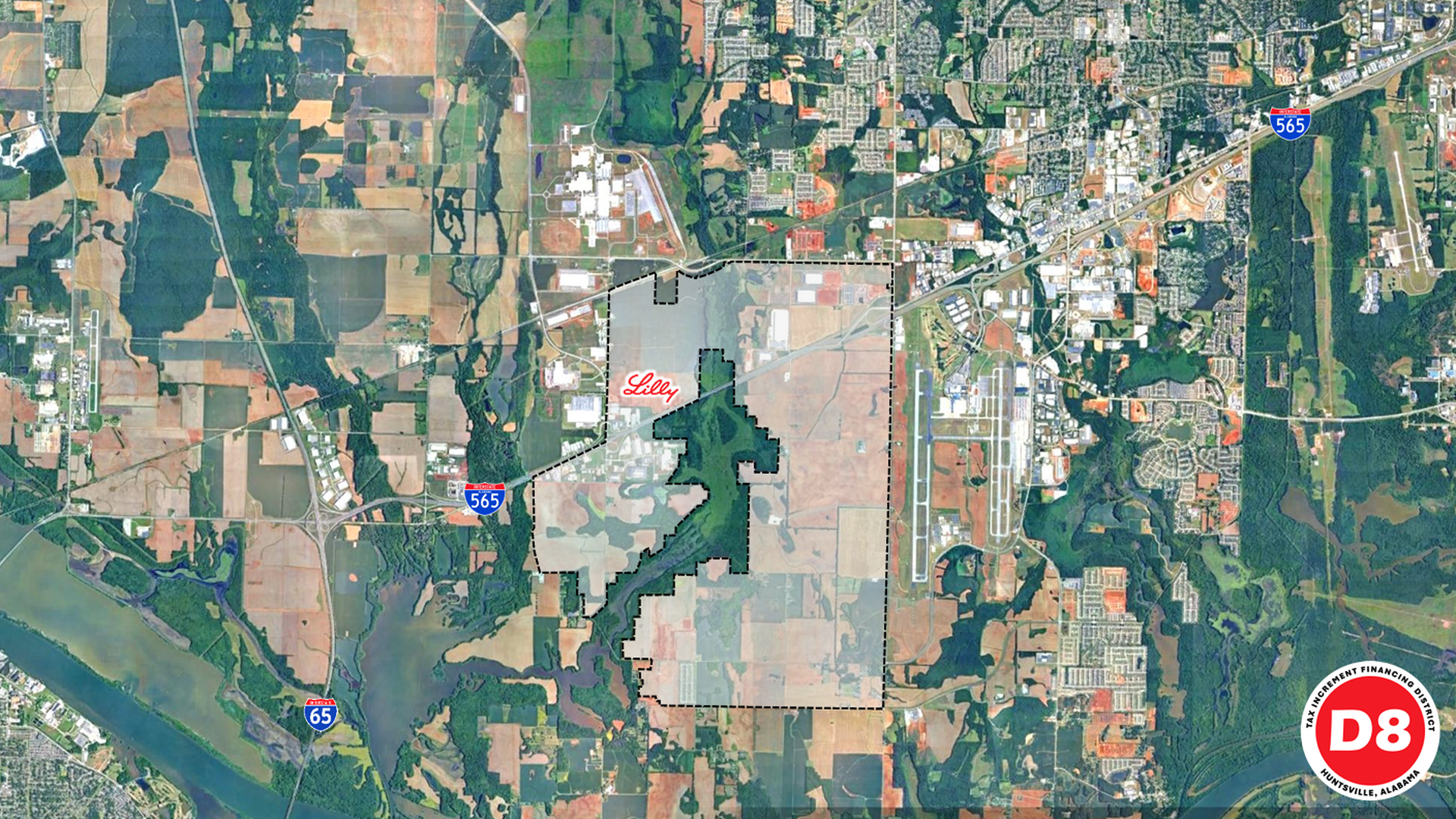 Satellite map with a large dashed-outline land parcel centered, containing a dark green forest patch; patchwork fields surround. Red "Lilly" label; nearby I-565 and I-65 highways; D8 logo bottom-right.