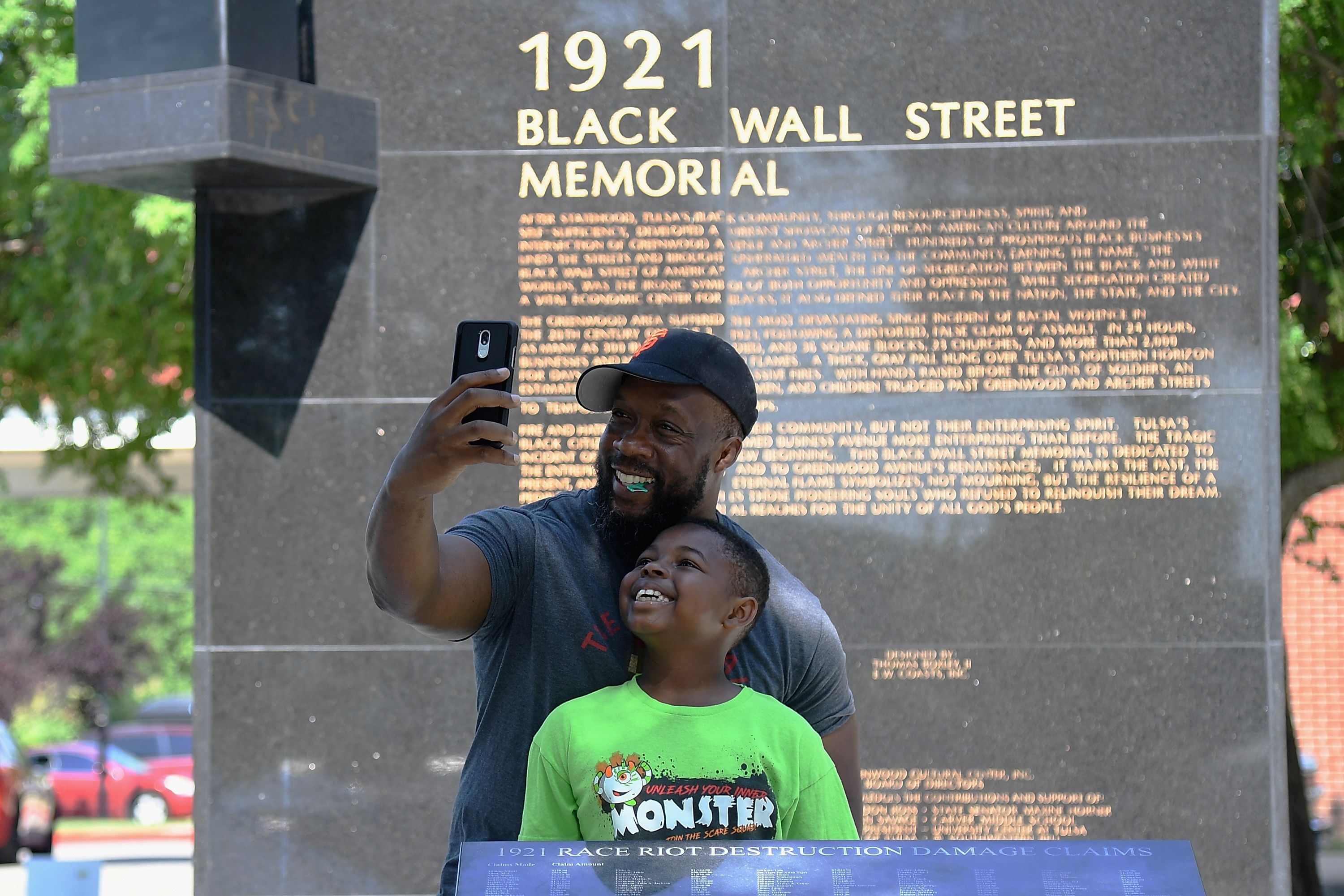 Picture of a father and son taking a selfie in from of the Black Wall Street Memorial in Tulsa, Oklahoma