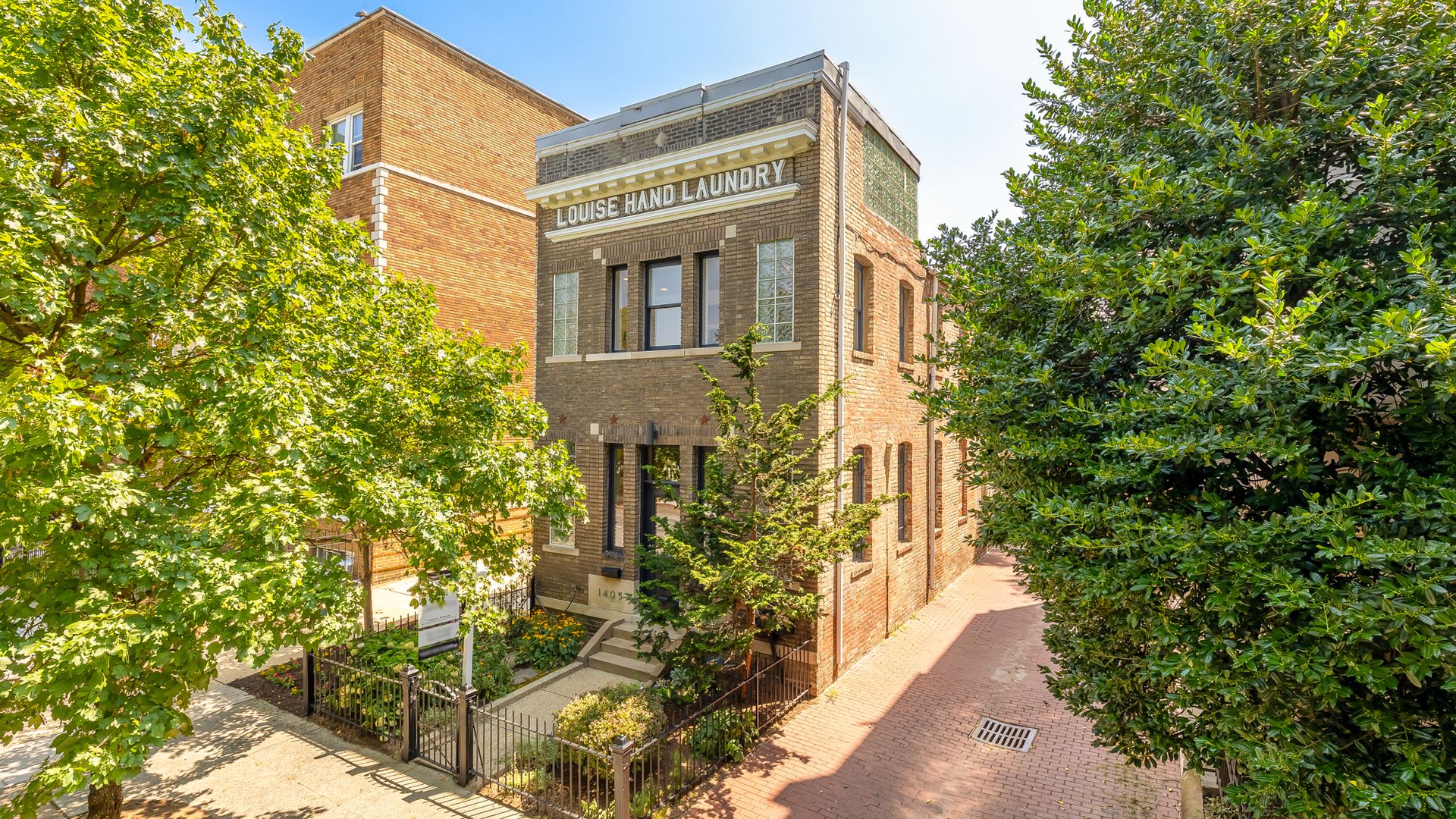 The exterior of a brick building that reads "Louise Hand Laundry."