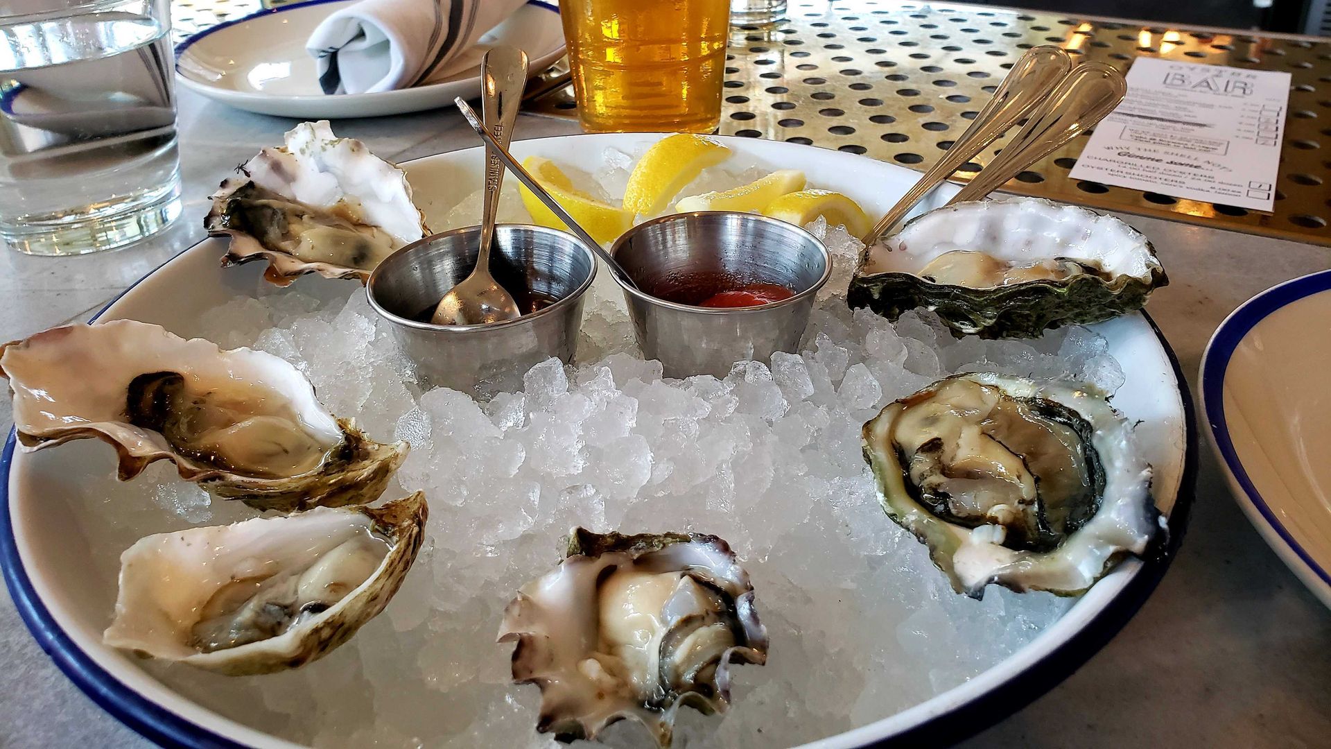 Photo of a plate of oysters next to a glass of beer. 
