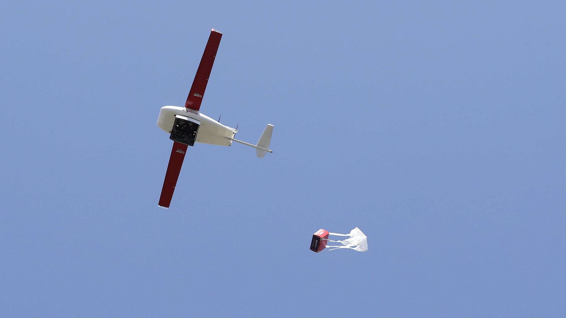 Image of a Zipline drone dropping a box of medical supplies via parachute.