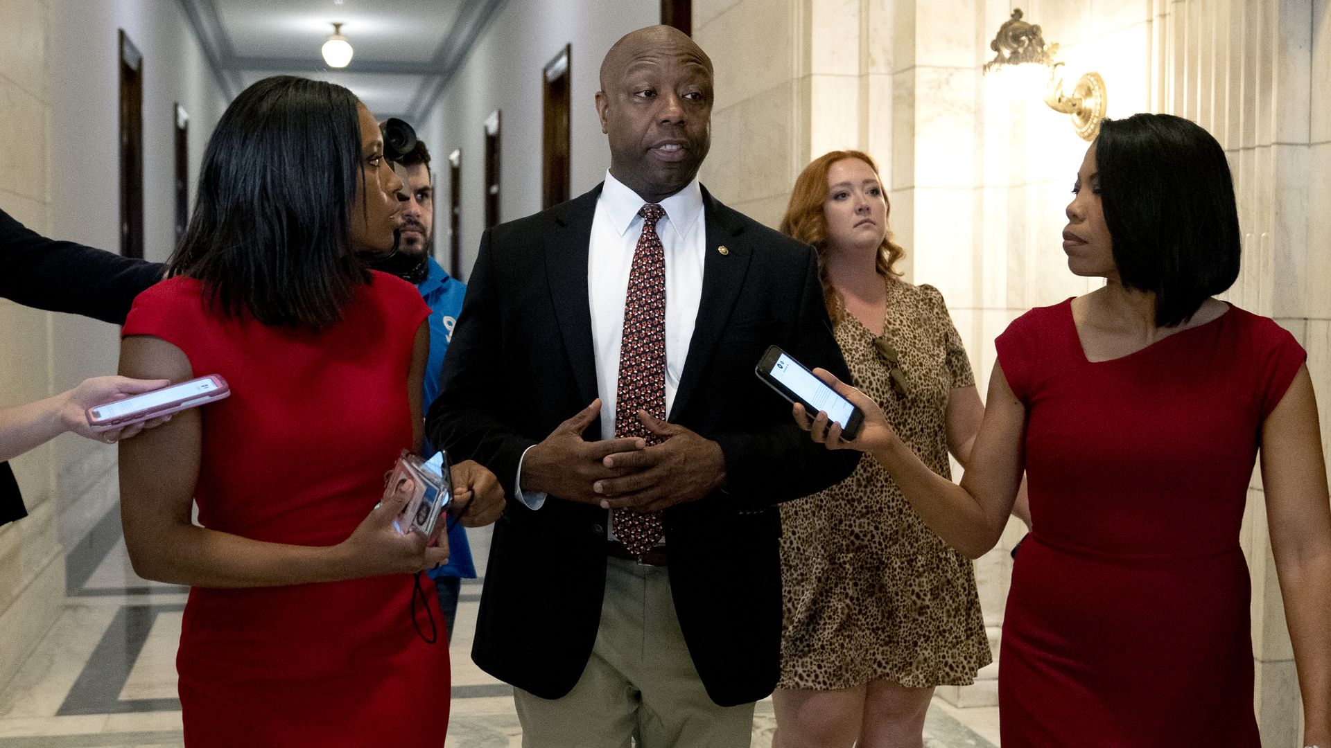 Sen. Tim Scott is seen speaking with reporters while walking through the Russell Office Building.