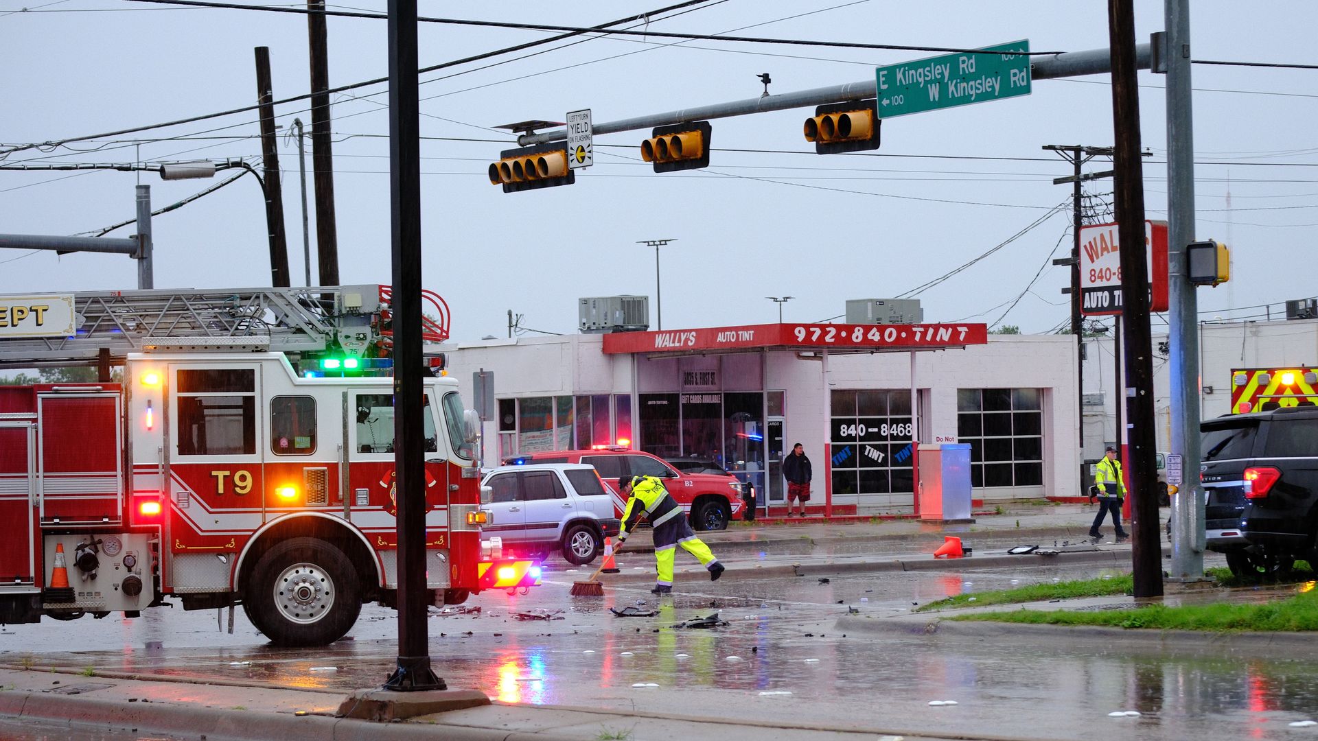 A fire truck parked in an intersection while firefighters clean up debris