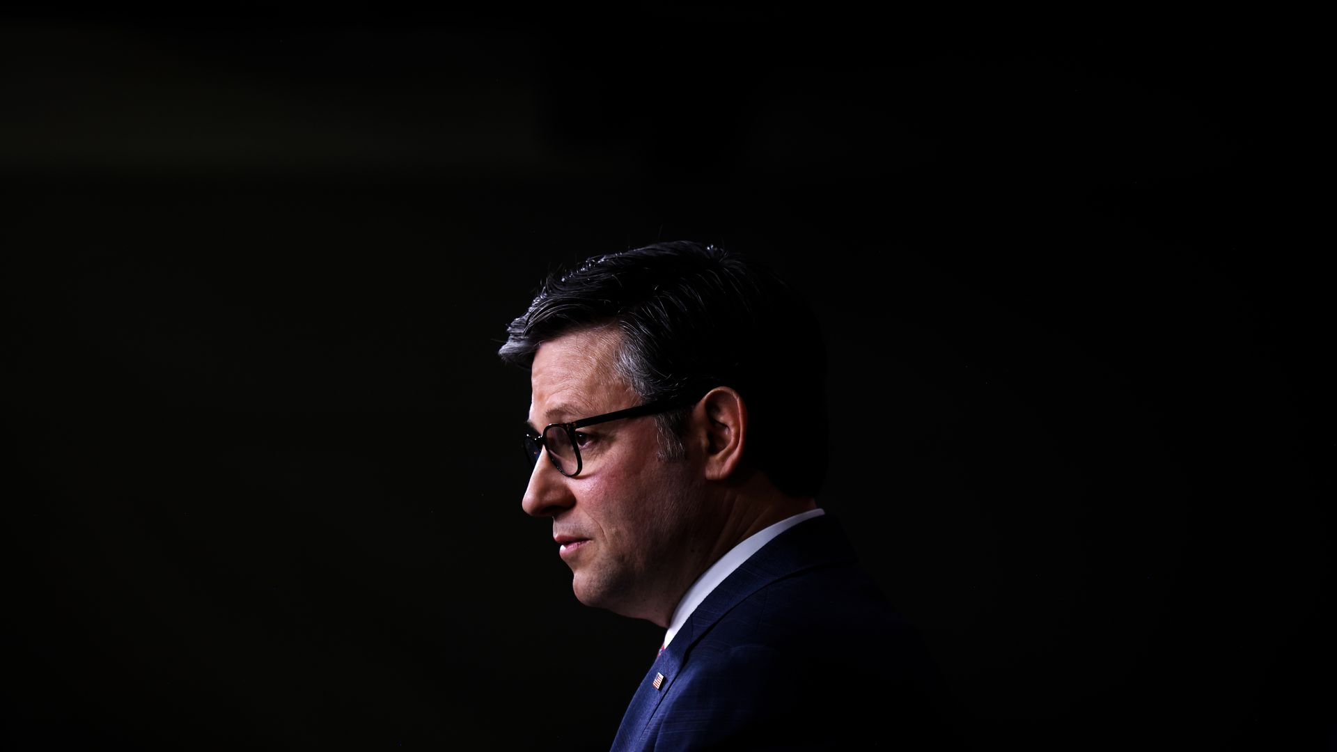 Mike Johnson, wearing a blue suit against a black backdrop.