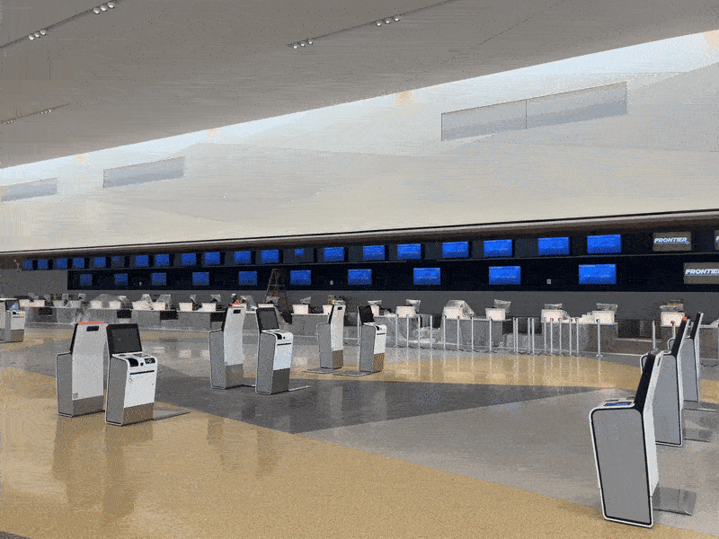 A gif shows an bright, airy and spacious check in area at an airport terminal with security lines in the background.