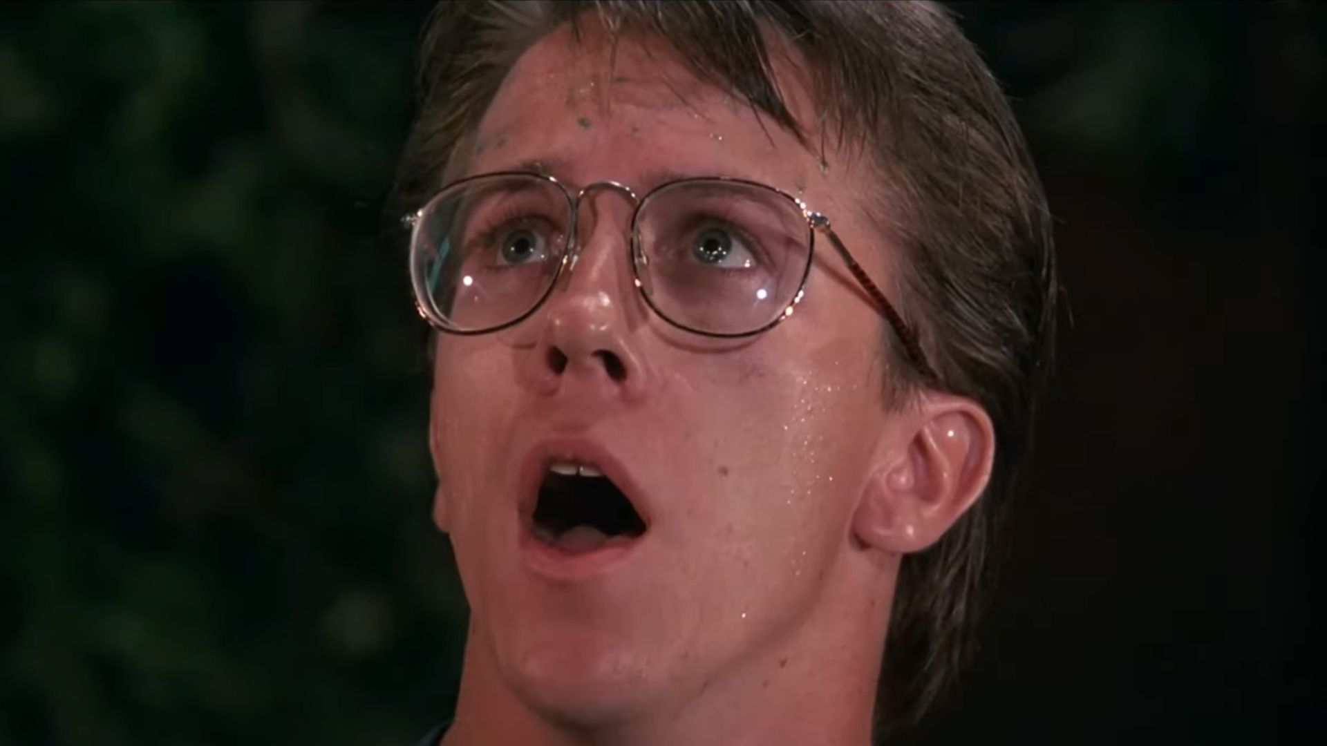 An actor with glasses gapes in horror at something above him.