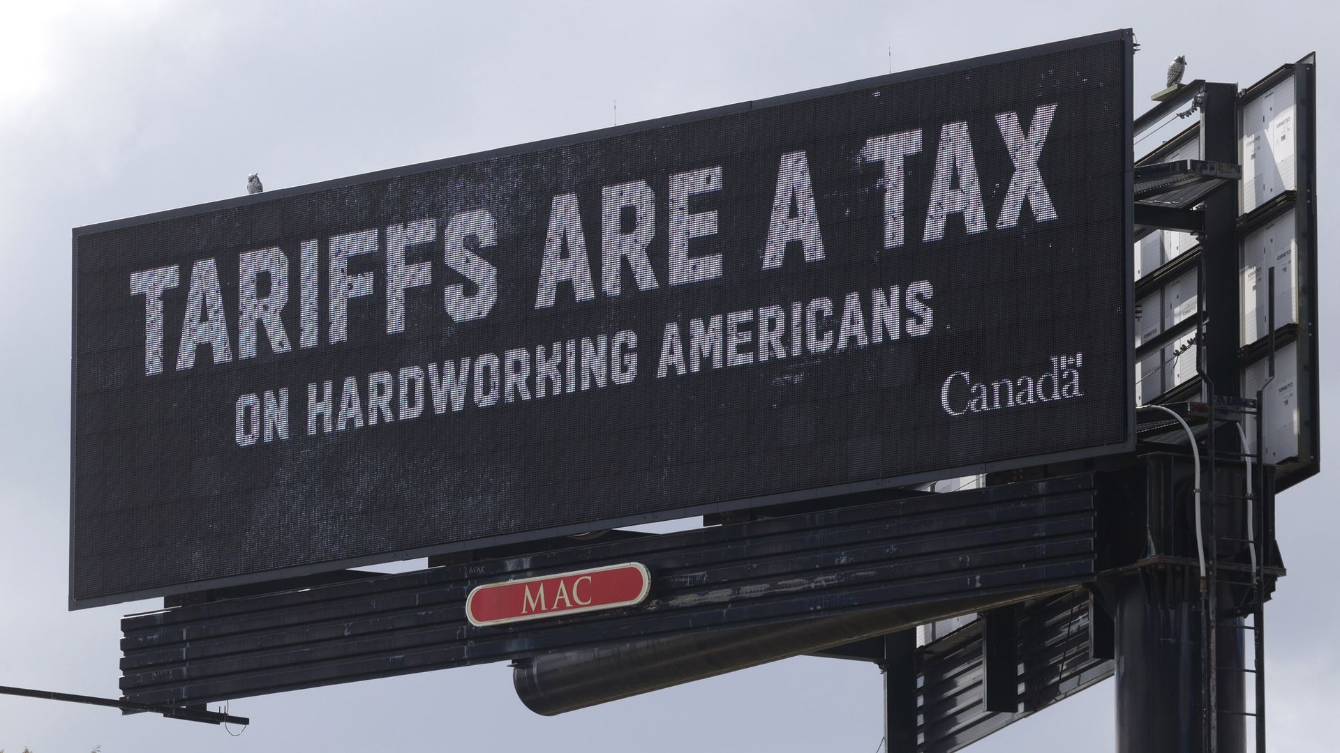 A picture of a billboard with the phrase 'Tariffs are a tax on hardworking Americans.'