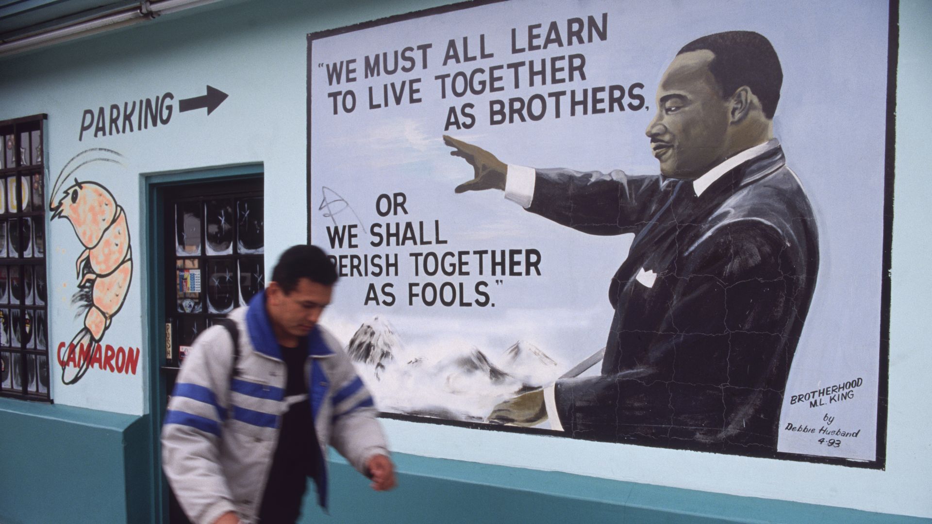 A Hispanic man walks with his bike passed an MLK mural in South Central Los Angeles.
