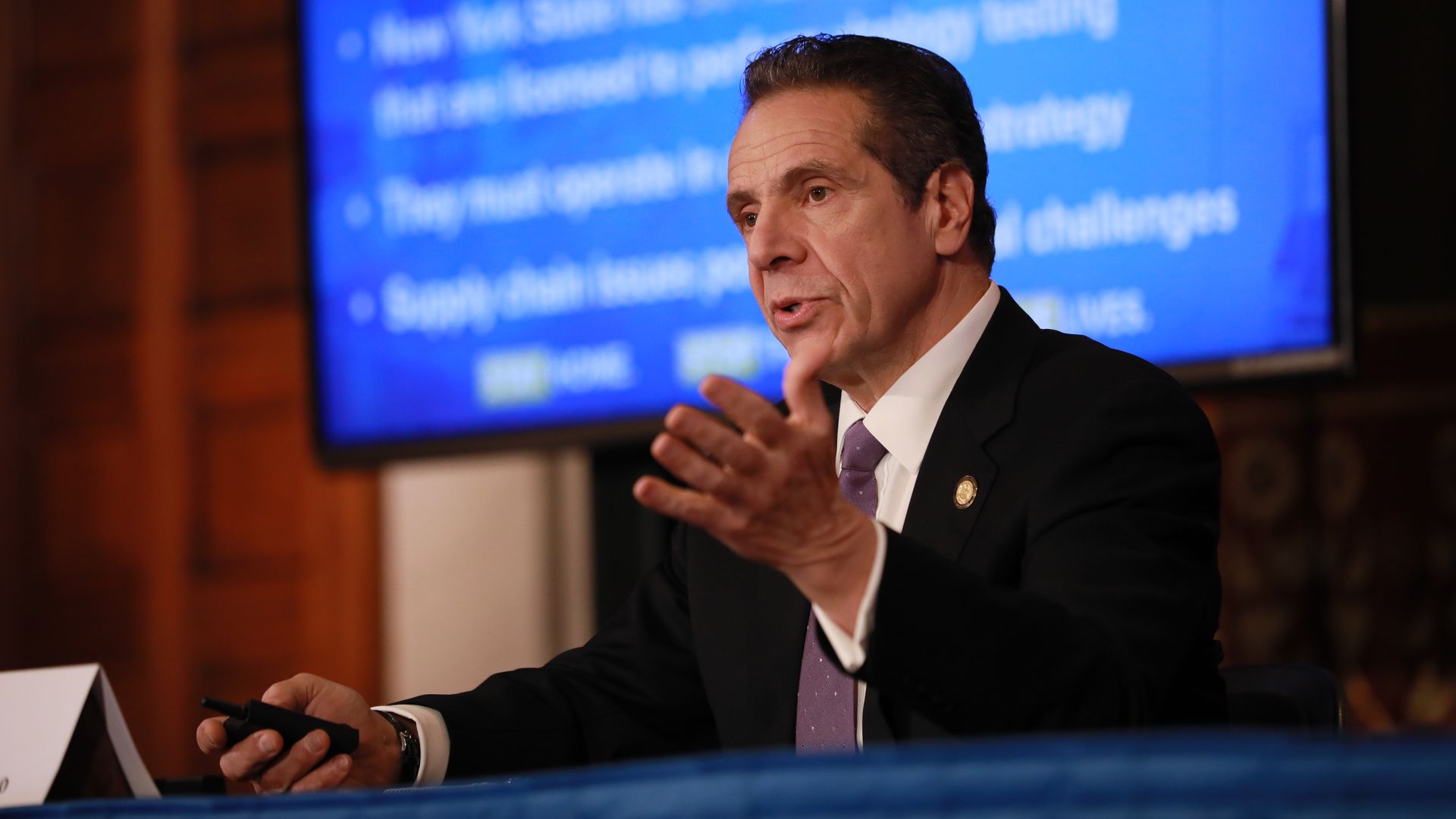 In this image, Gov. Andrew Cuomo talks in front of a presentation screen
