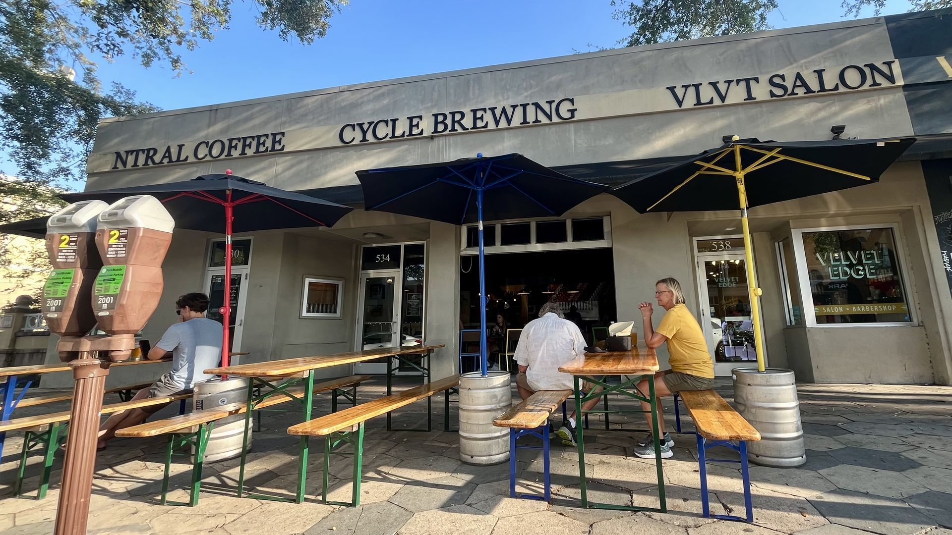 A storefront with a sign that says "CYCLE BREWING" with picnic tables and umbrellas out front.