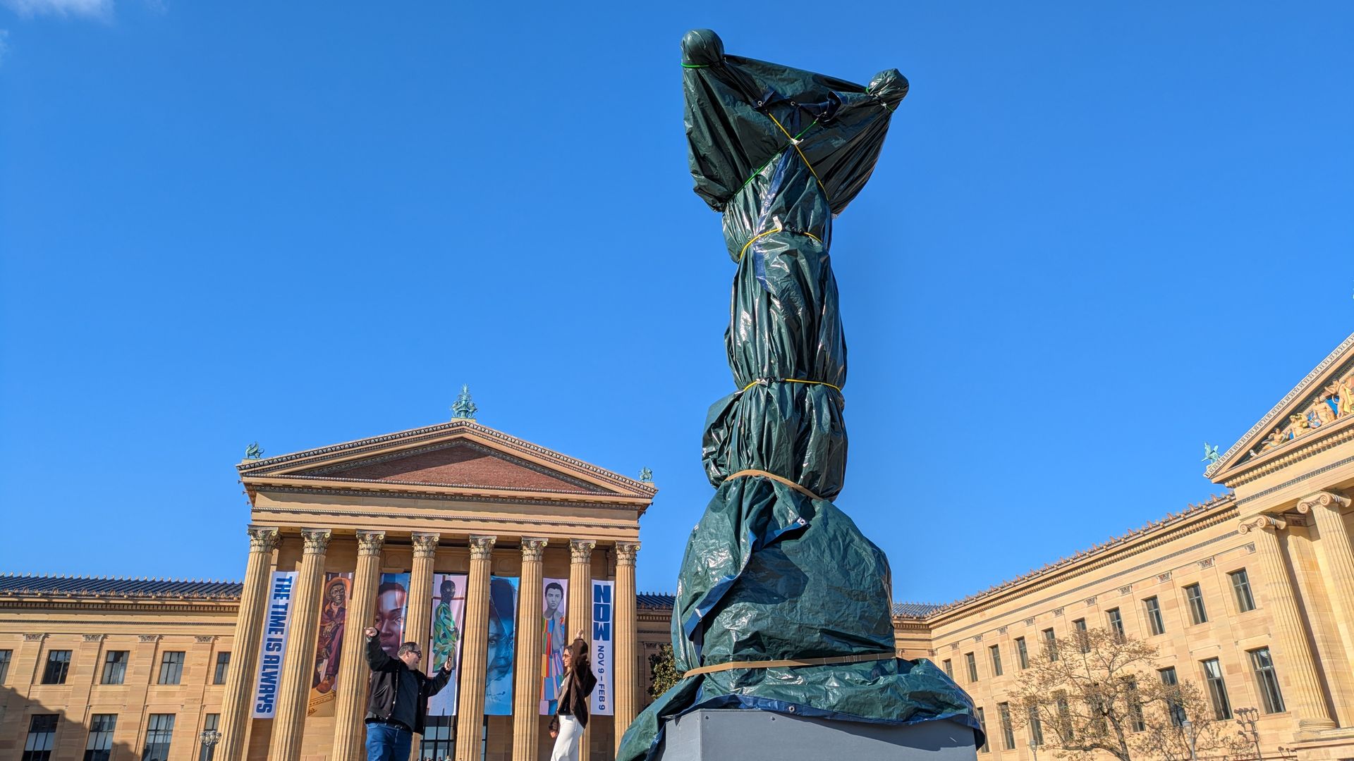 A statue stands covered at the top of the Philadelphia Museum of Art steps 